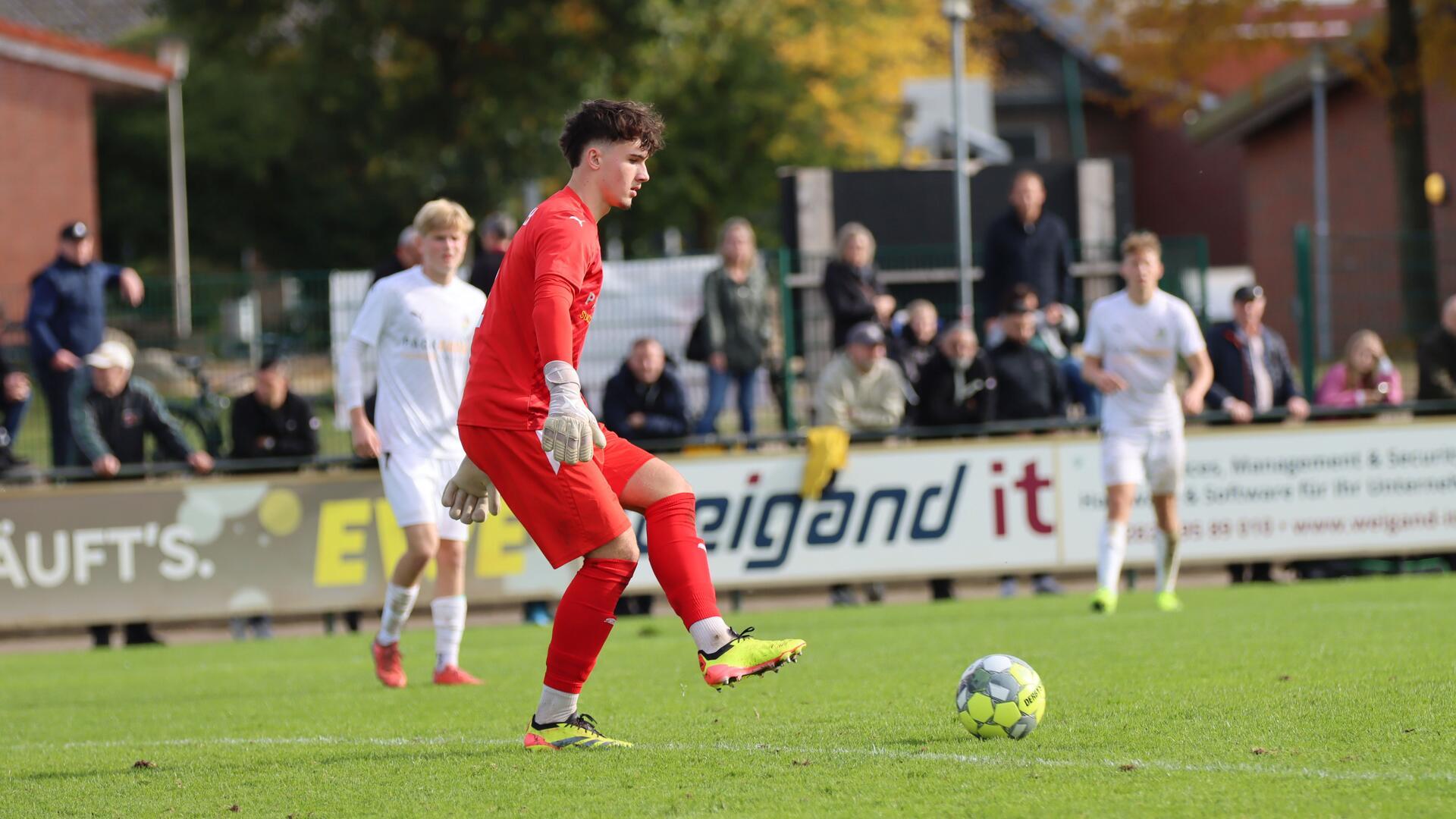 Ein Mann in rotem Trikot schießt einen Ball.