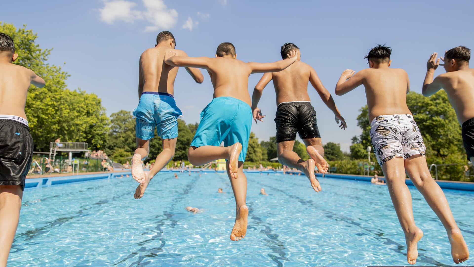 Sechs Jungen springen ins Wasser.