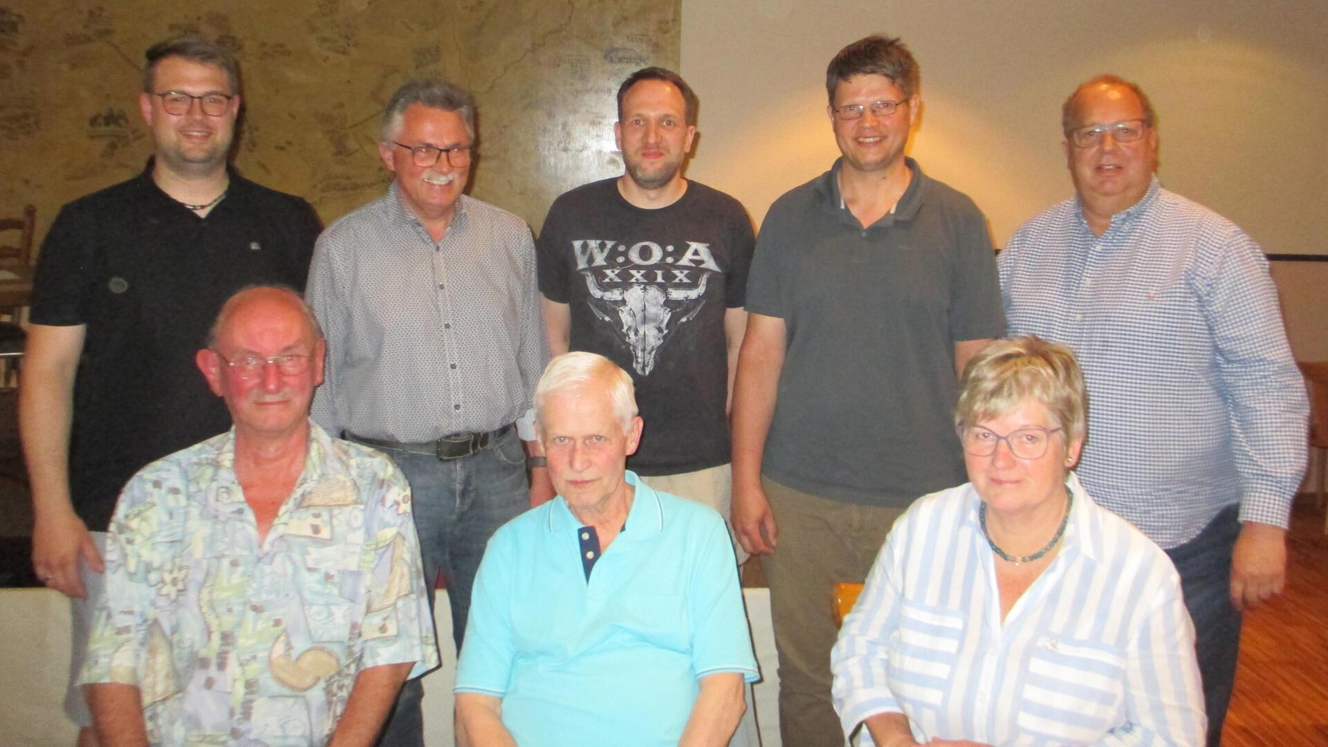 Gruppenbild mit sieben Männern und einer Frau, die in zwei Reihen stehen.