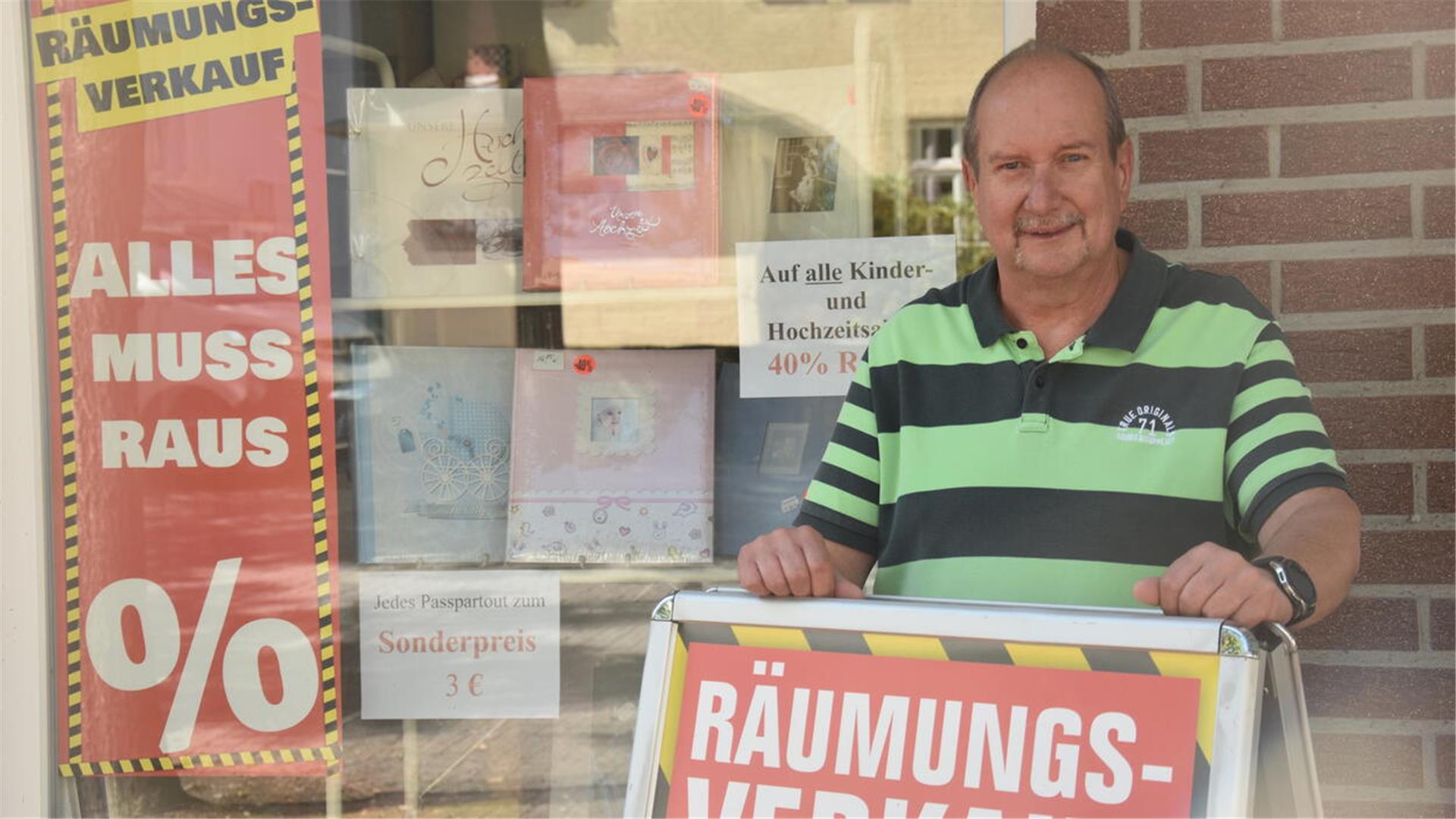 Peter Kleefeld hält vor seinem Geschäft ein Schild mit dem Schriftzug Räumungsverkauf. 