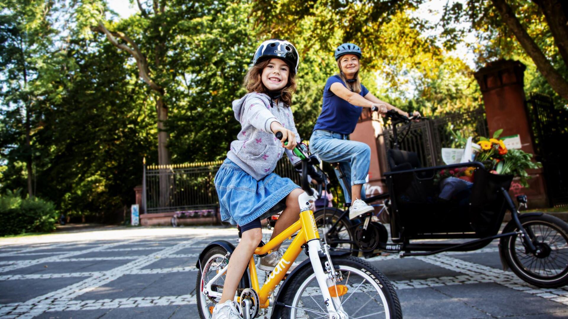 Mädchen auf Fahrrad und Frau auf Lastenrad