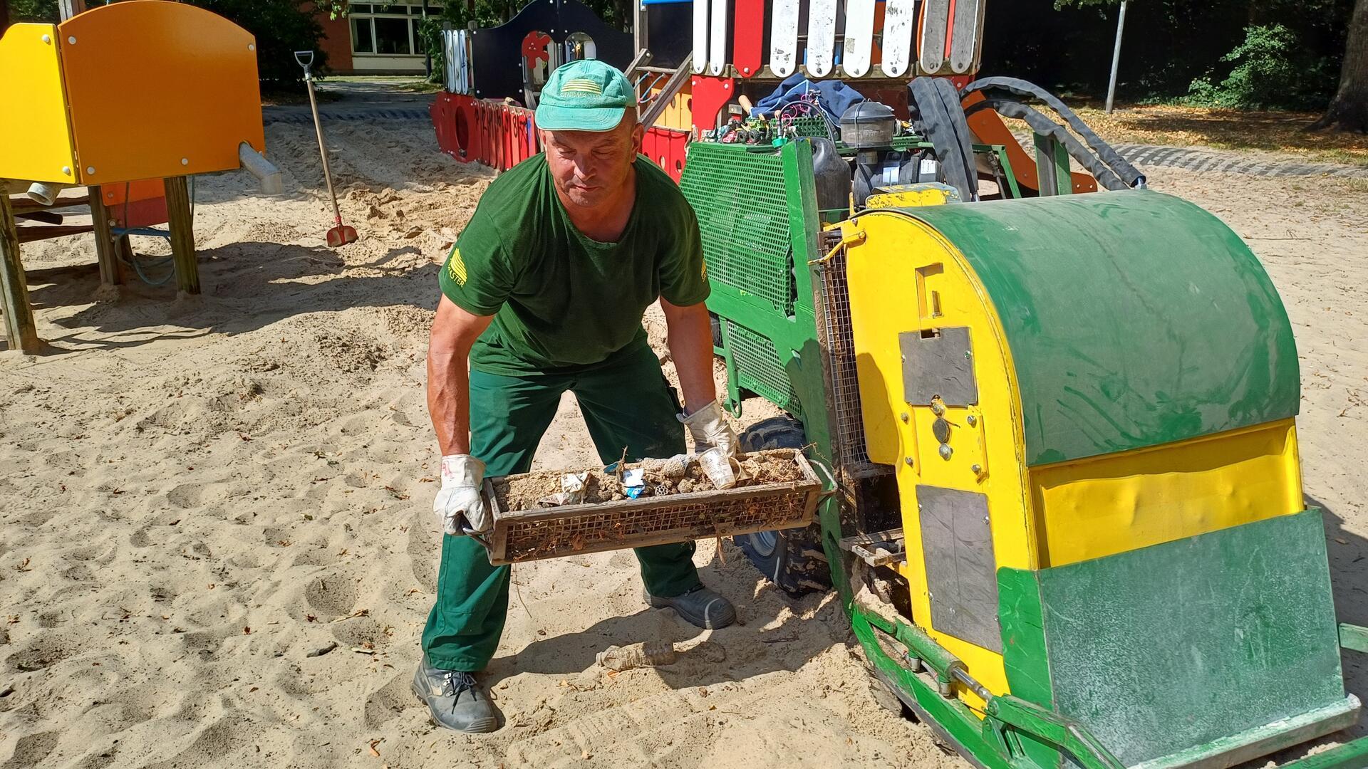 Ein Arbeiter auf einem Sandspielplatz.