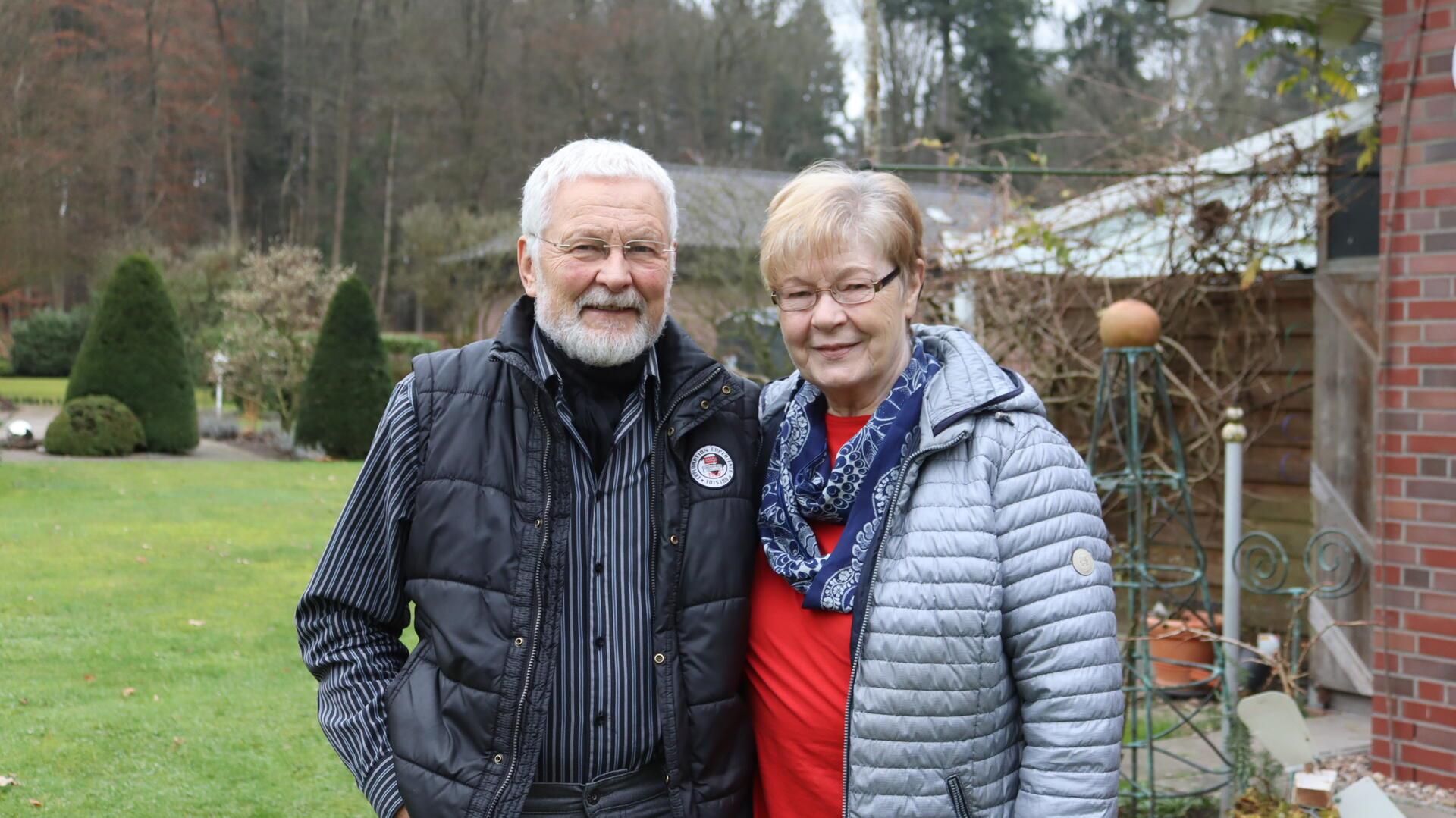 Älteres Ehepaar im Garten lächelt in Kamera