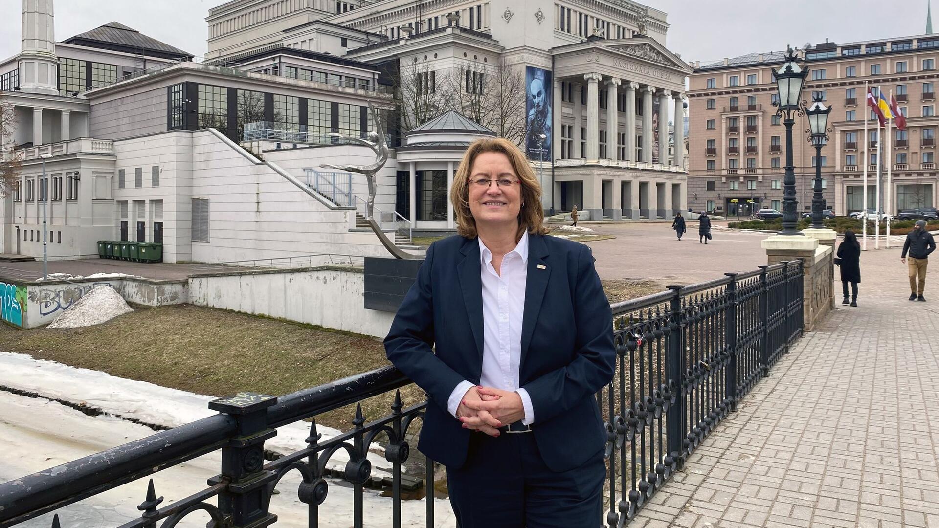 Antje Grotheer steht während ihres Besuchs in Riga auf einer Brücke vor der lettischen Nationaloper.