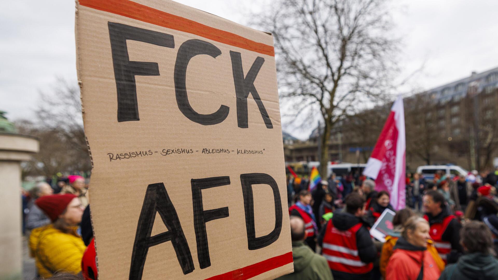 Auf einer Demonstration hält jemand ein Plakat mit der Aufschrift "FCK AFD" in die Kamera.