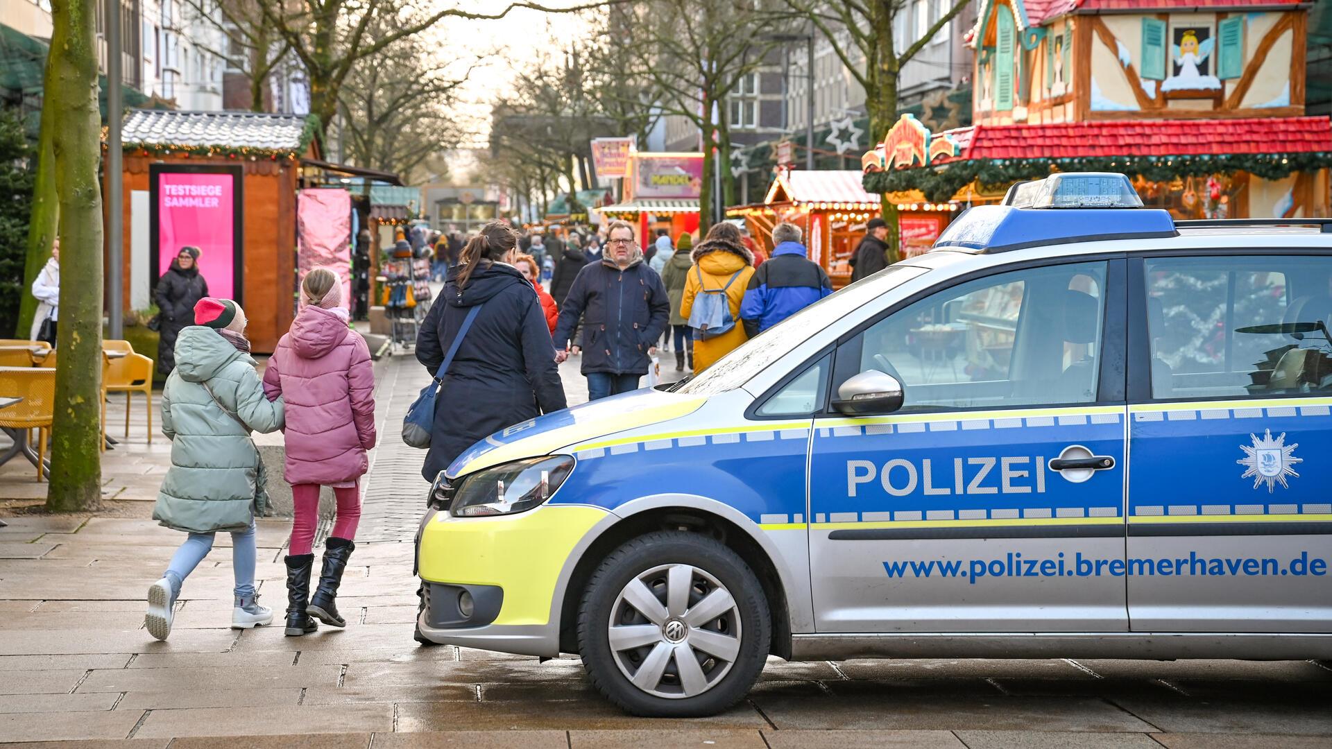 Ein Polizeiauto vor einem Weihnachtsmarkt. 