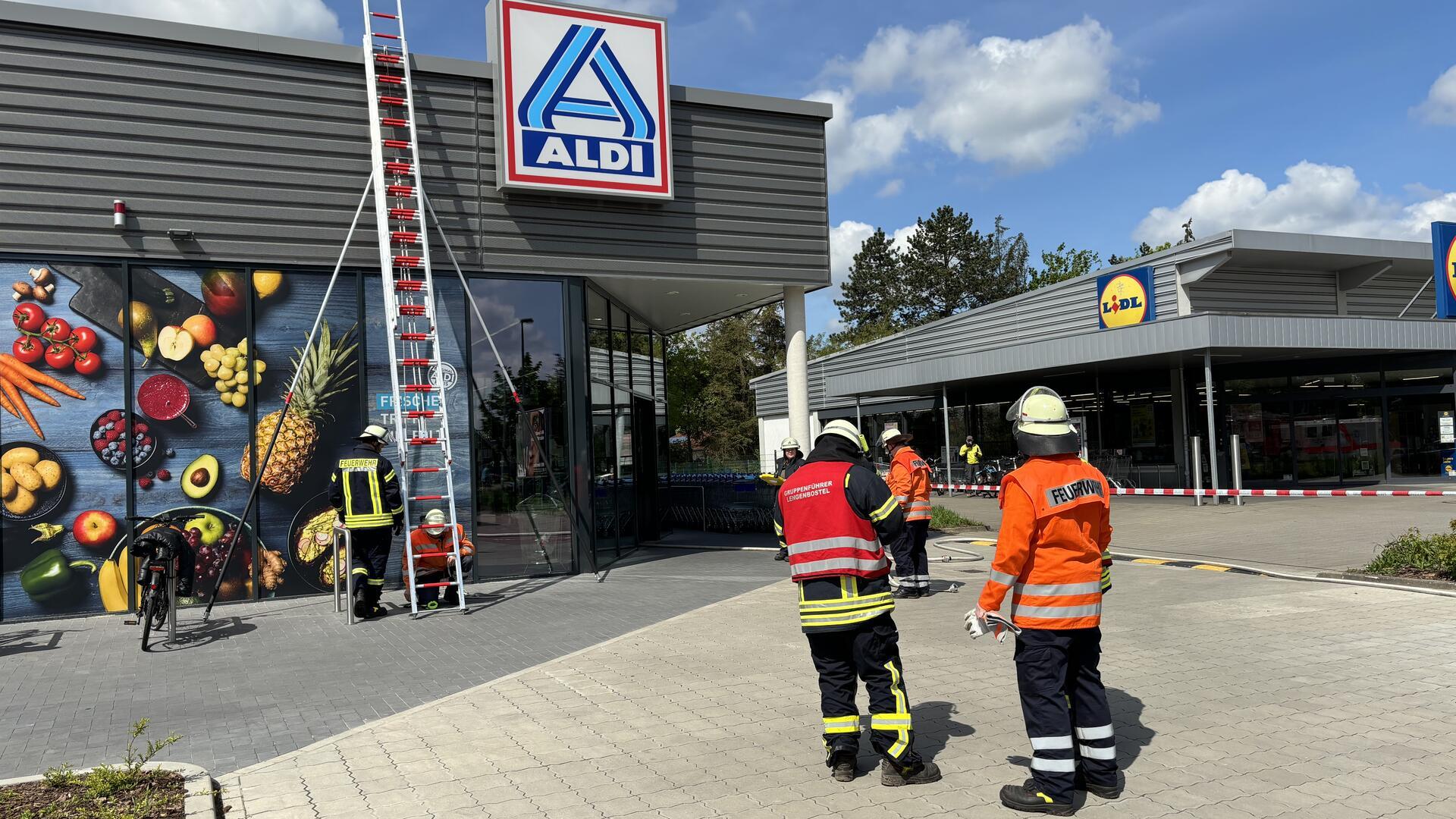 Das Foto zeigt zwei Feuerwehrleute vor dem Aldi-Markt. 