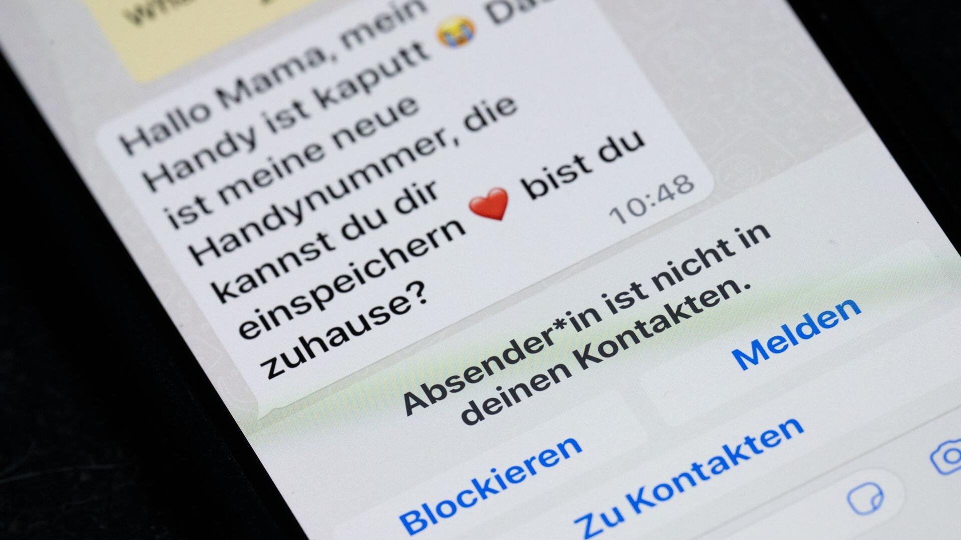 Auf dem Display eines Smartphones steht eine Whats App-Nachricht, die im Tonfall betrügerischen Nachrichten nachempfunden ist.