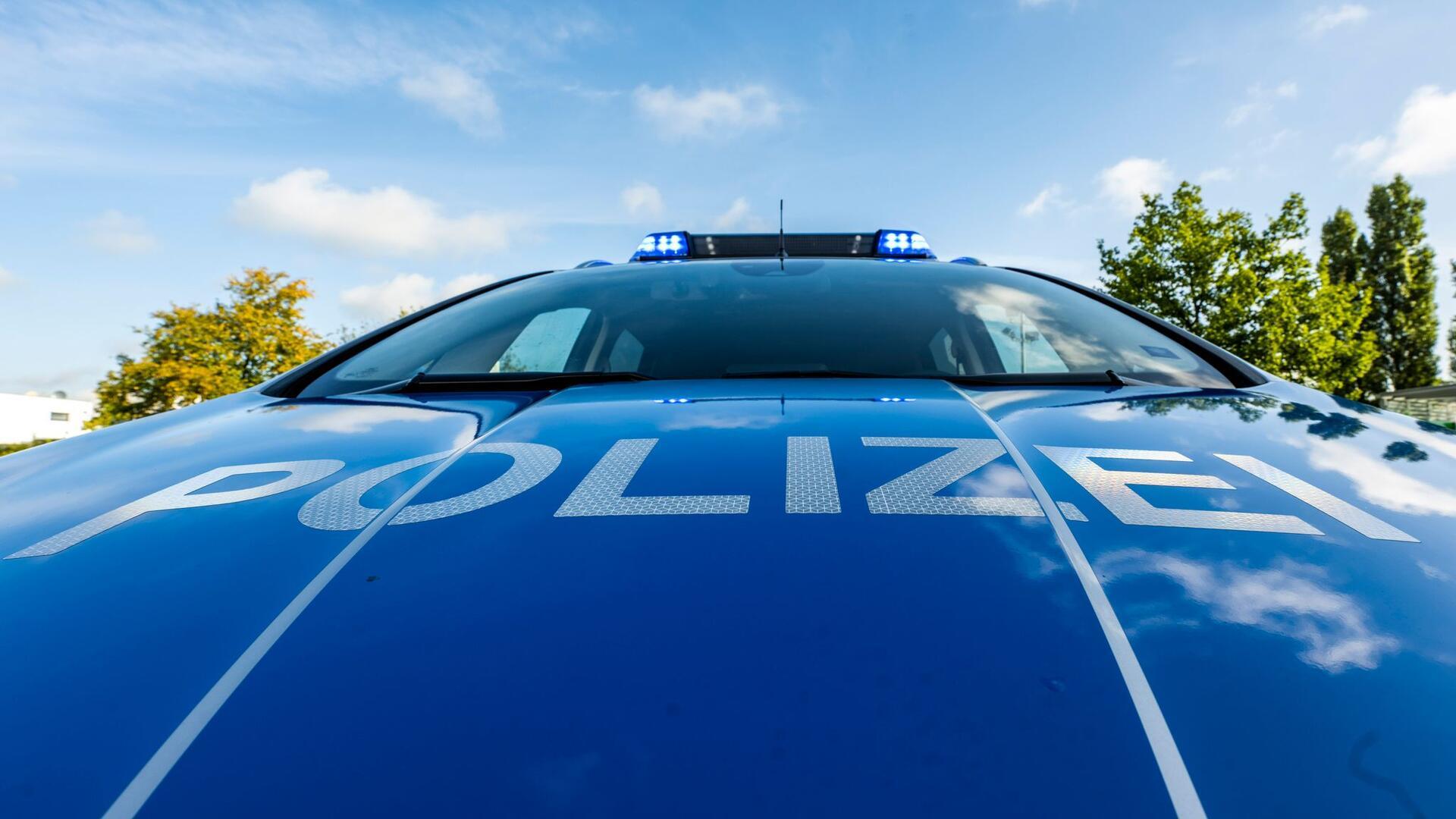 Auf der Motorhaube eines Streifenwagens steht der Schriftzug „Polizei“.