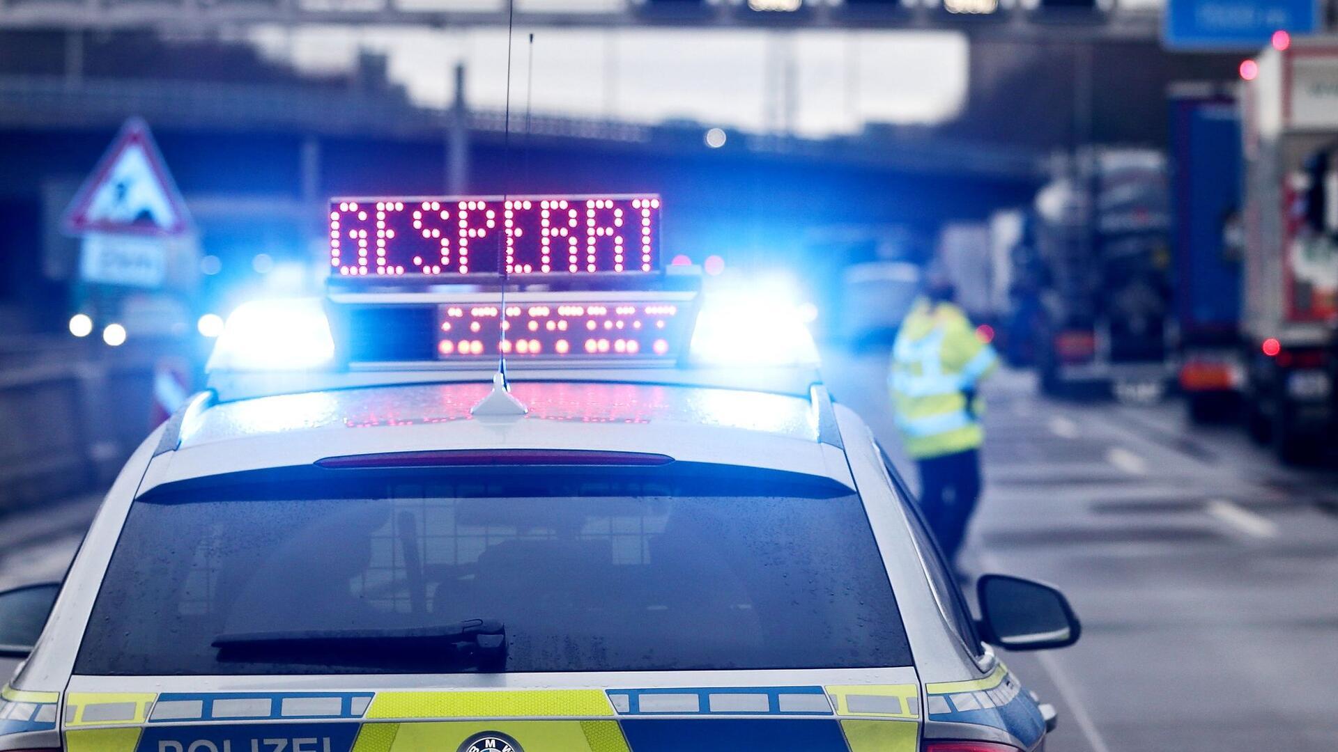 Auf einem Polizeifahrzeug leuchtet die Aufschrift „Gesperrt“.