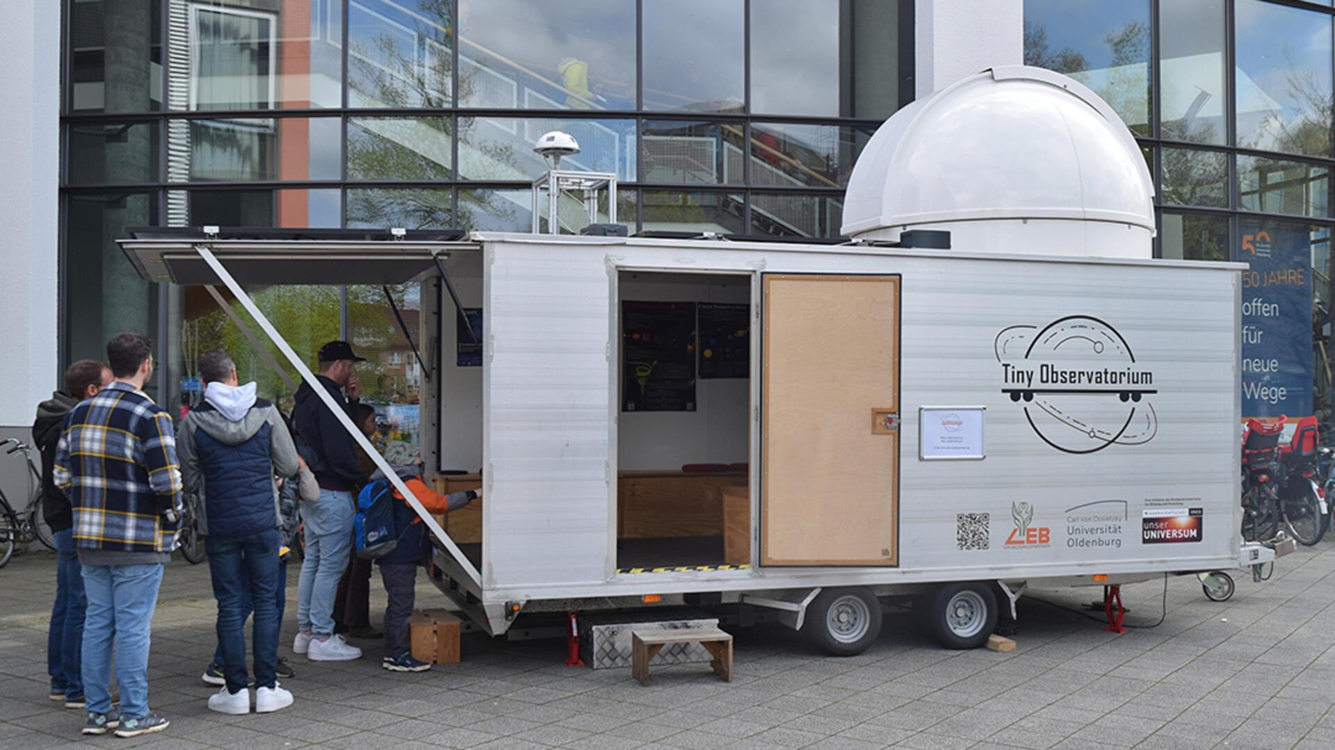 4 Männer werfen einen Blick in mobiles Observatorium.