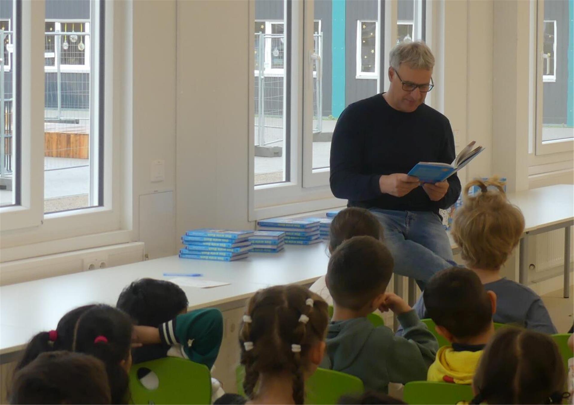 Marco Bode liest Schulkinder ein Buch vor 