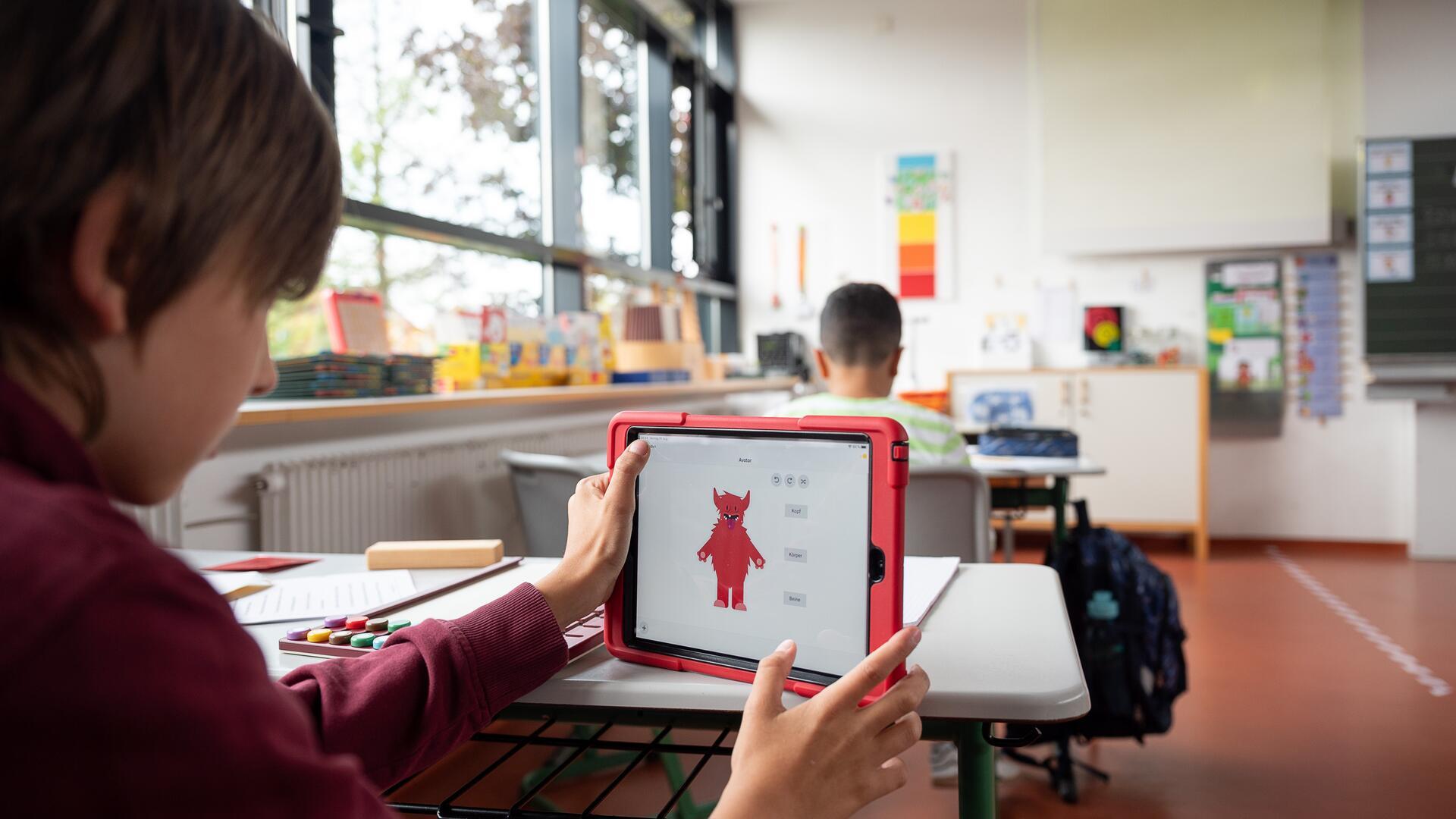 Grundschüler arbeiten mit dem iPad im Unterricht. 