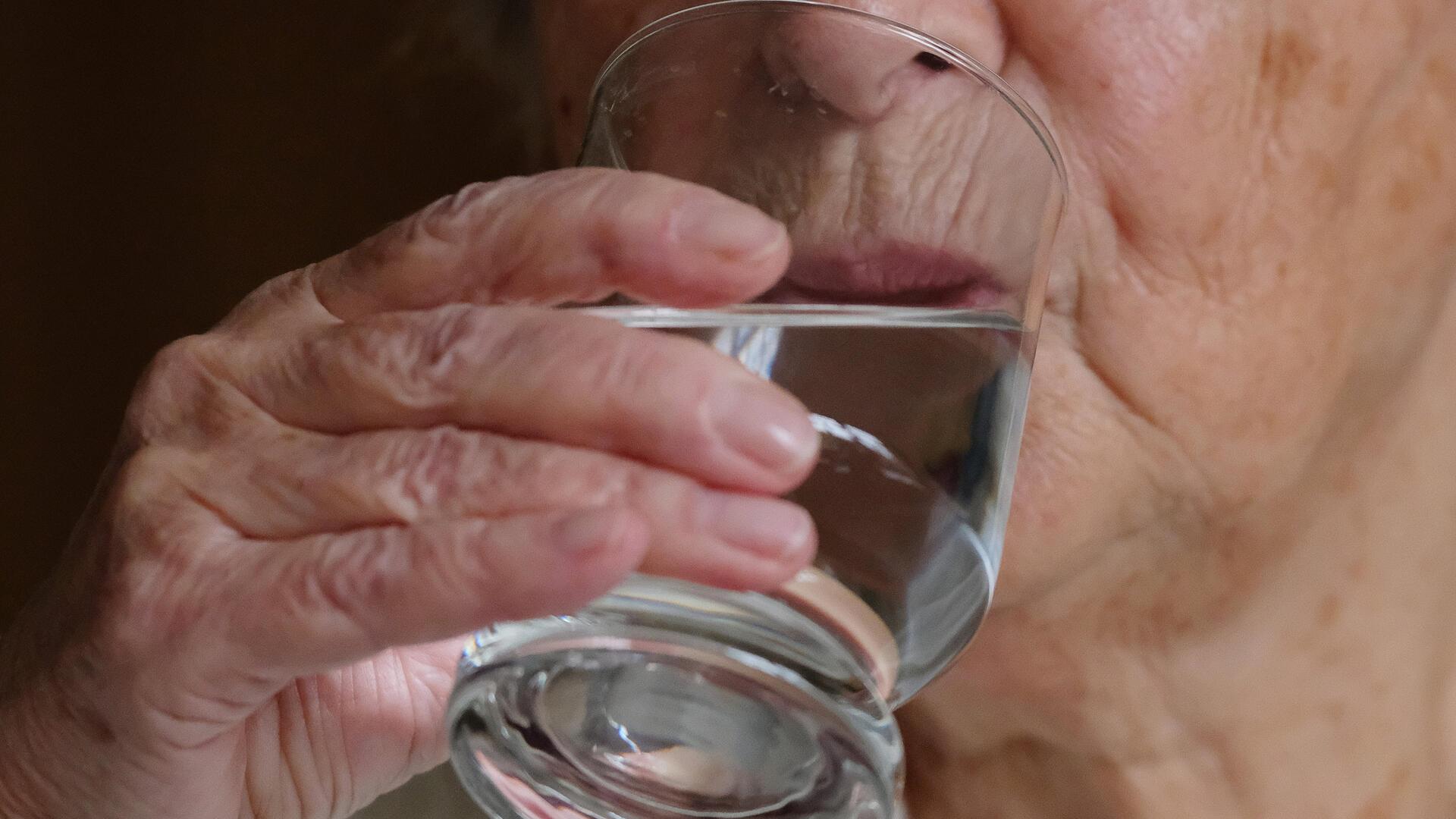 Person trinkt aus Wasserglas