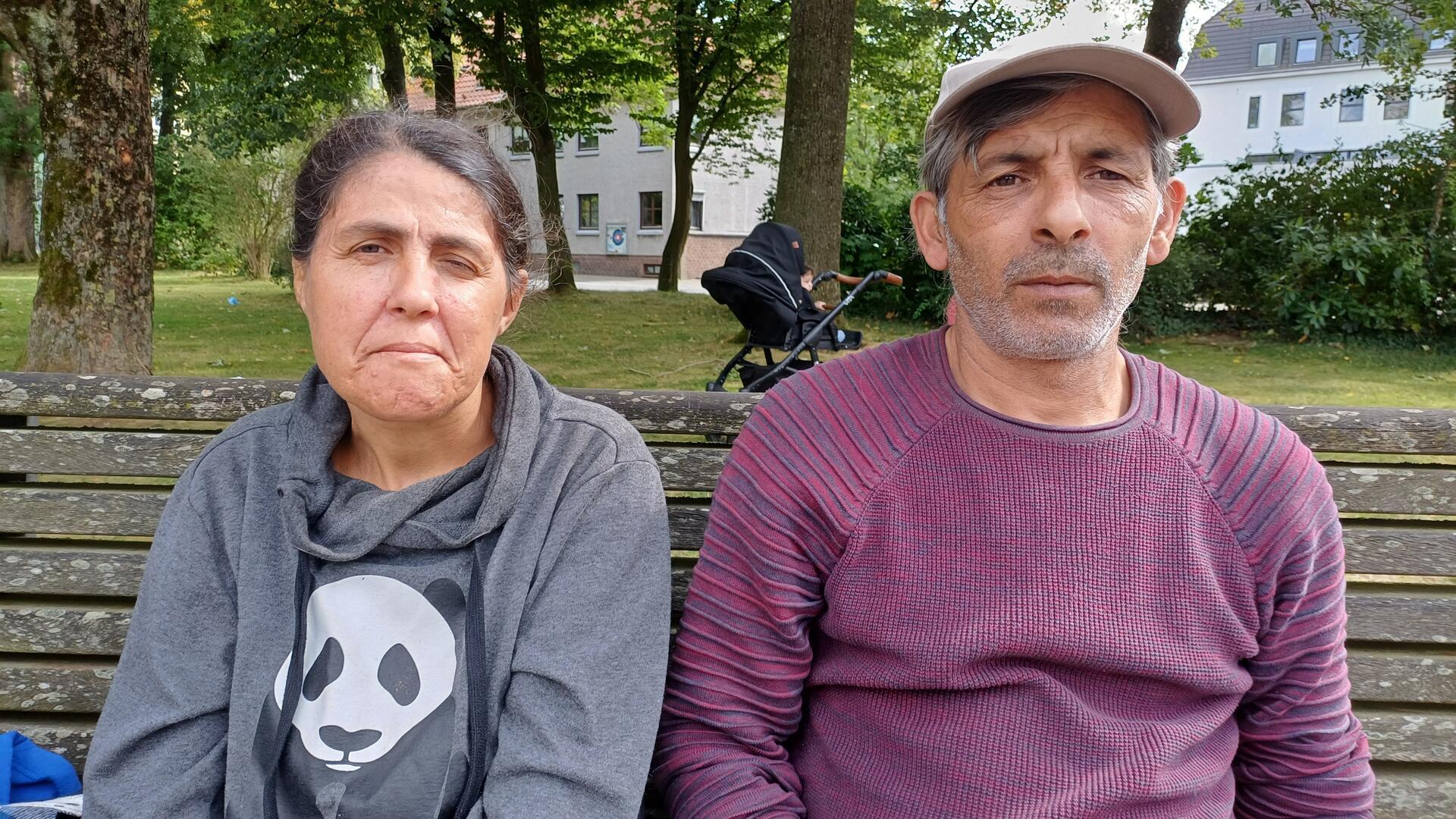 Eine Frau und ein Mann sitzen auf einer Parkbank.