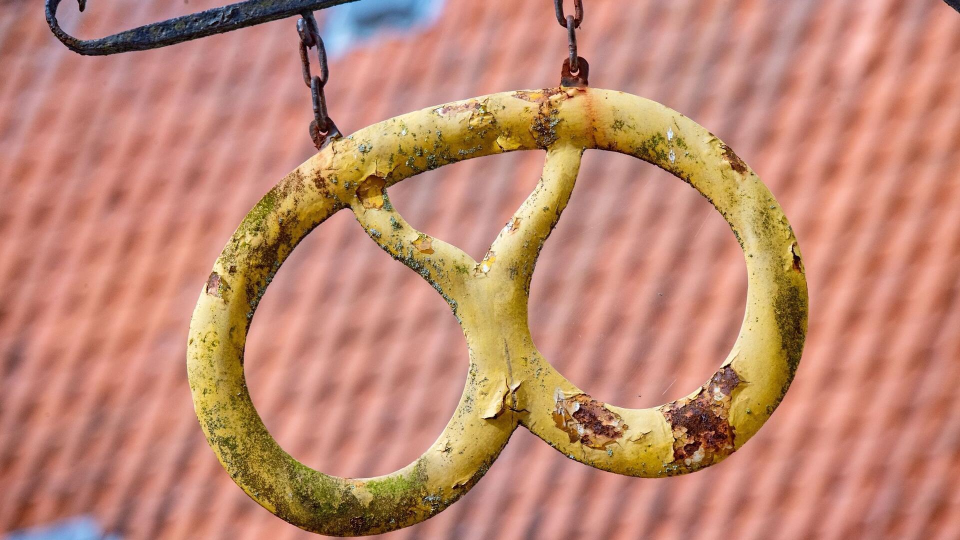 Eine Brezel hängt wie ein Aushängeschild vor einer Bäckerei.