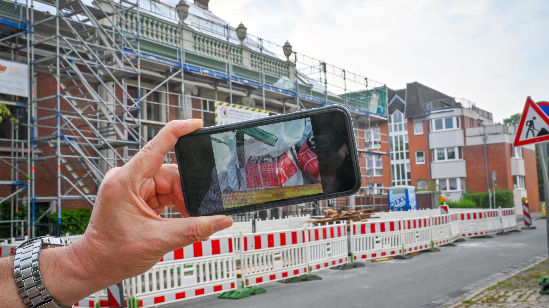 Ein Handy, im Hintergrund ein Haus mit Baugerüst.