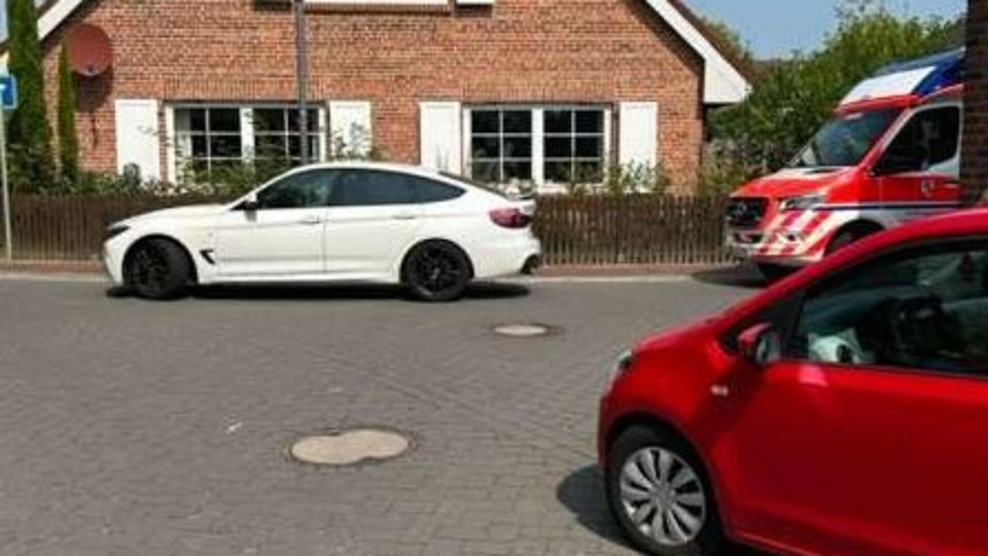 Auf einer Straße stehen ein weißes, ein rotes Auto und ein Rettungswagen.