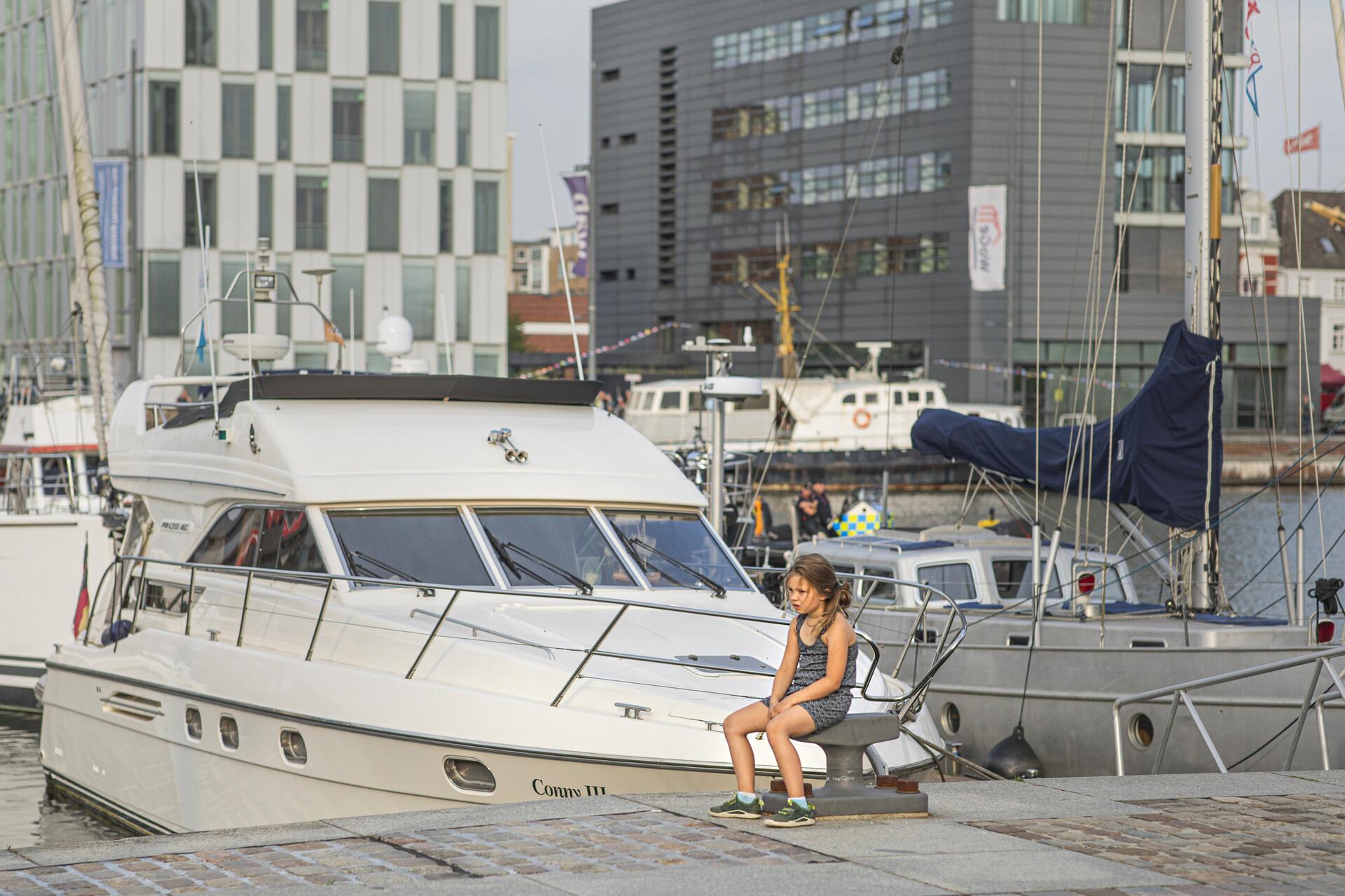 Ein Mädchen sitzt am Hafen. 