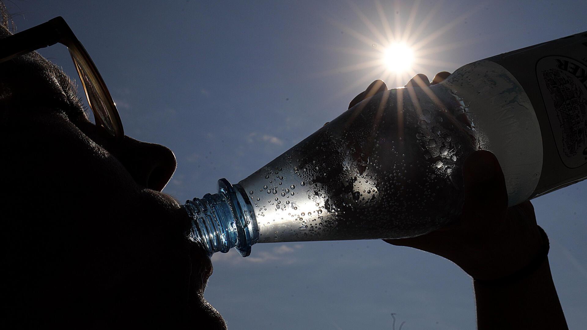 Eine Person trinkt aus einer Flasche Mineralwasser