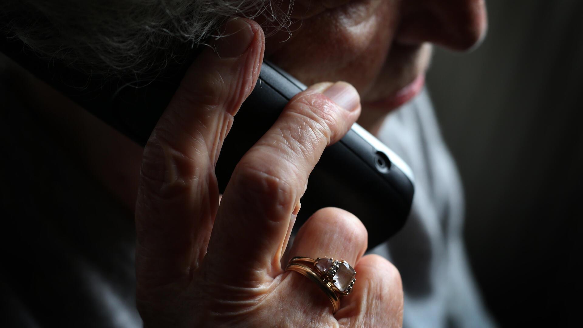 Eine ältere Dame hält ein Handy am Ohr. 