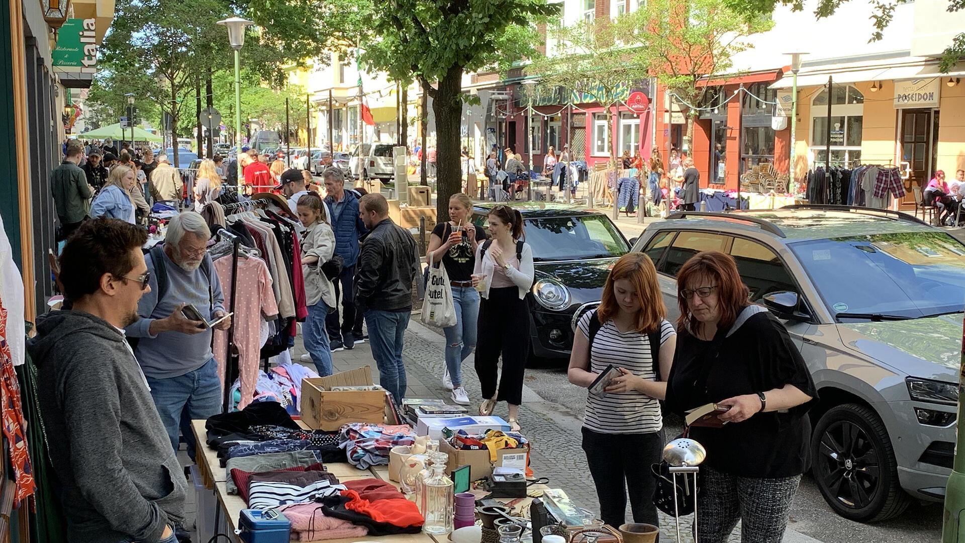 Besucherinnen und Besucher stöbern an mehreren Flohmarktständen in der Straße "Alte Bürger"