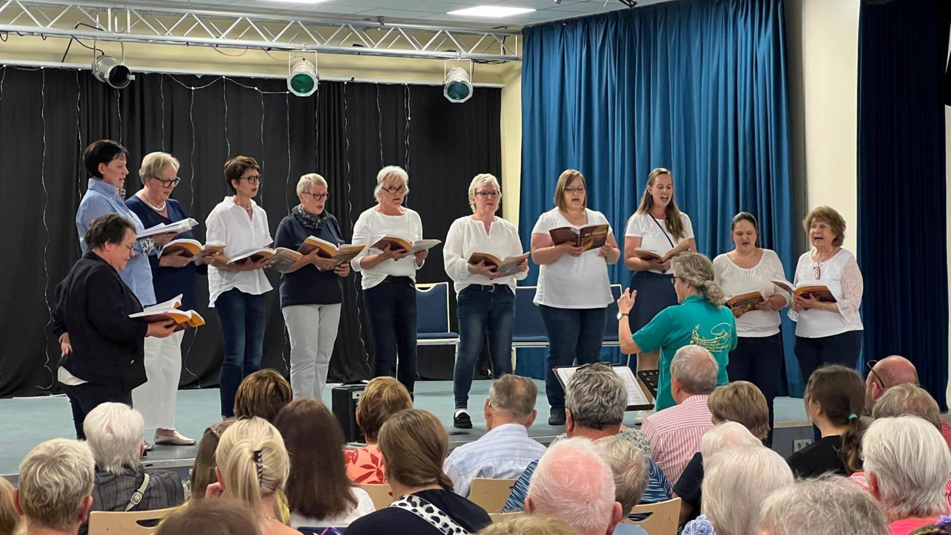 Frauen stehen auf der Bühne und singen ein Chorkonzert.