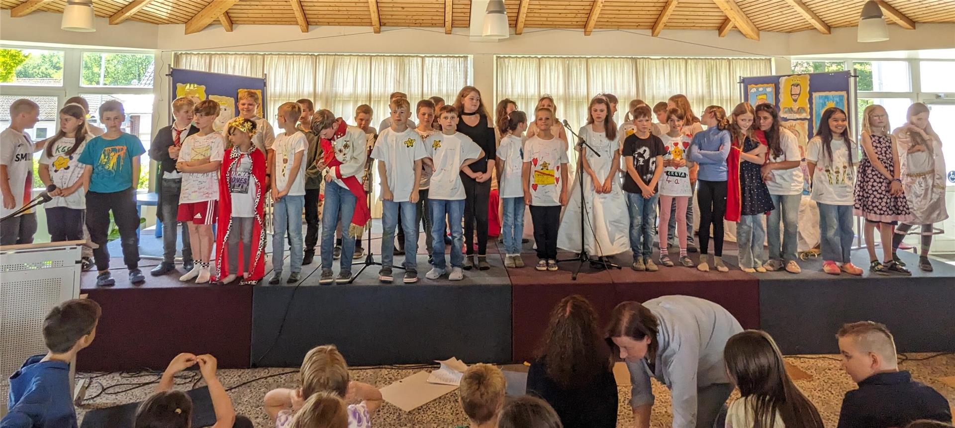 Die Grundschüler stehen auf der Bühne und singen ein Lied. 