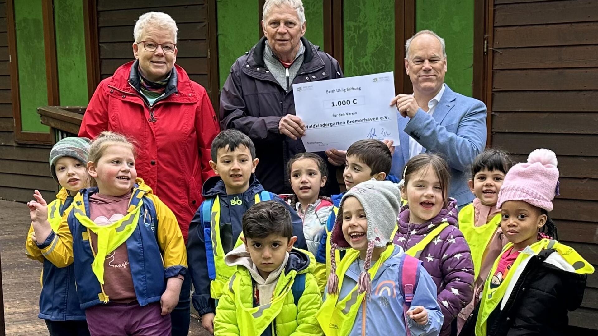 Vorstandsmitglied Birgit Külcke und der 1. Vorsitzende Wilfried Töpfer vom Förderverein des Waldkindergartens Bremerhaven freuen sich mit den Kindern über die Spende, die Jens Grotelüschen von der Edith Uhlig Stiftung übergibt.