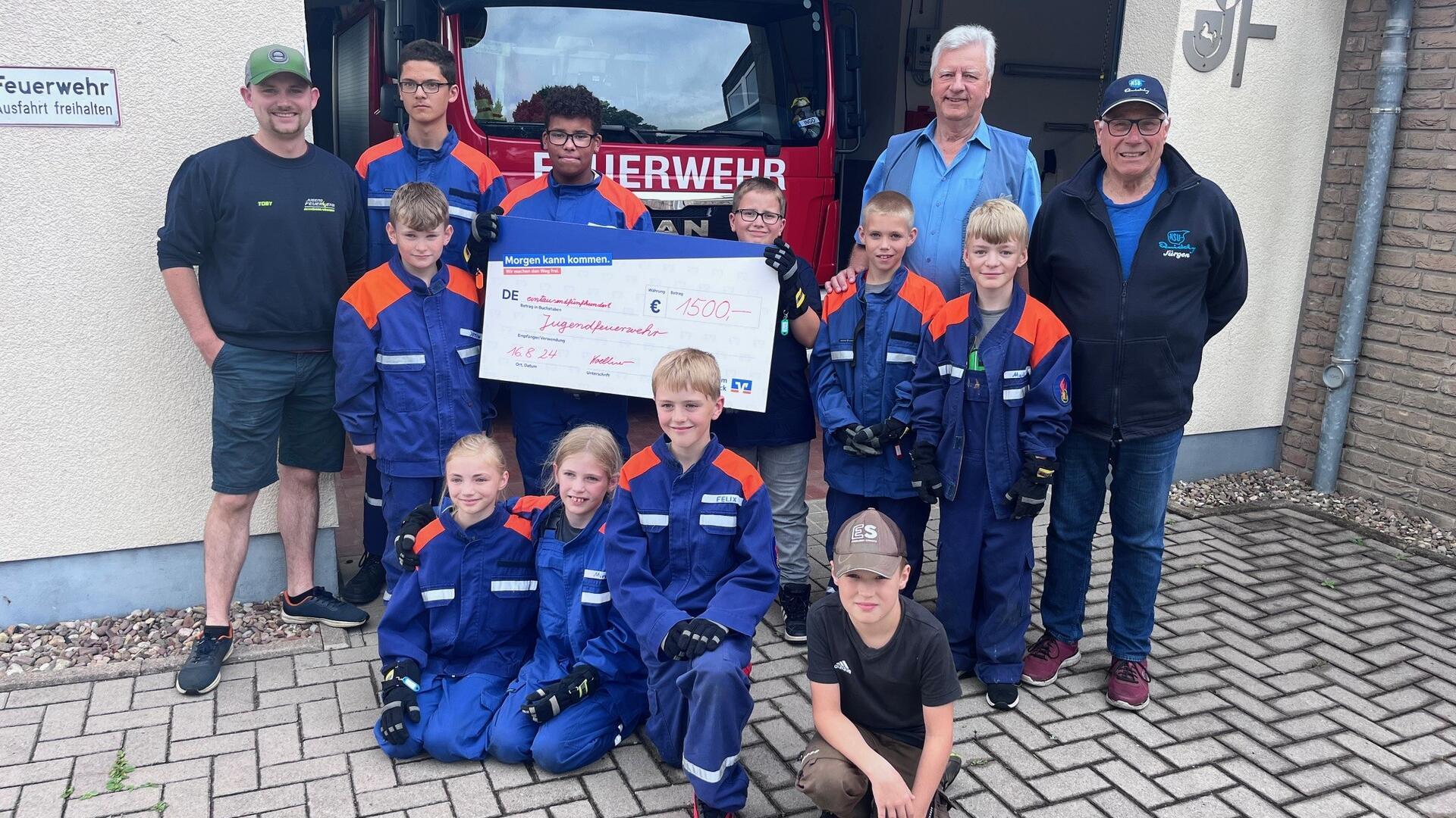 Gruppenfoto von Jugendlichen in Feuerwehruniform und Erwachsenen vor einem Feuerwehrfahrzeug