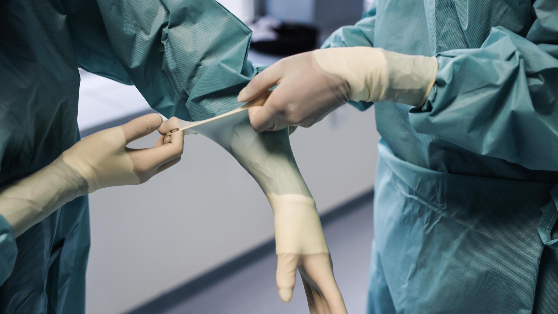 Ärzte ziehen OP-Handschuhe an. 