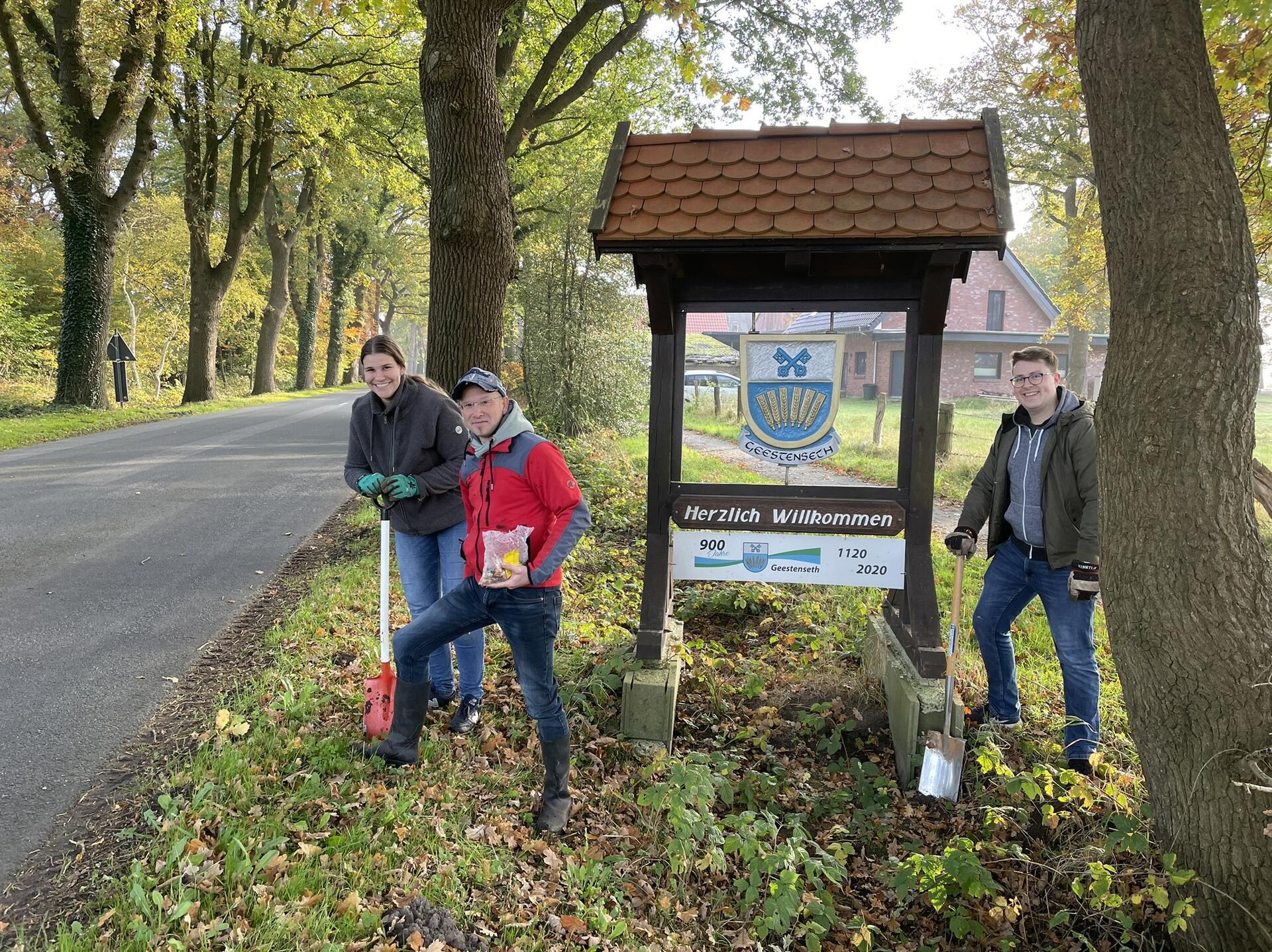 Drei Männer an einer Straße mit einem Schild