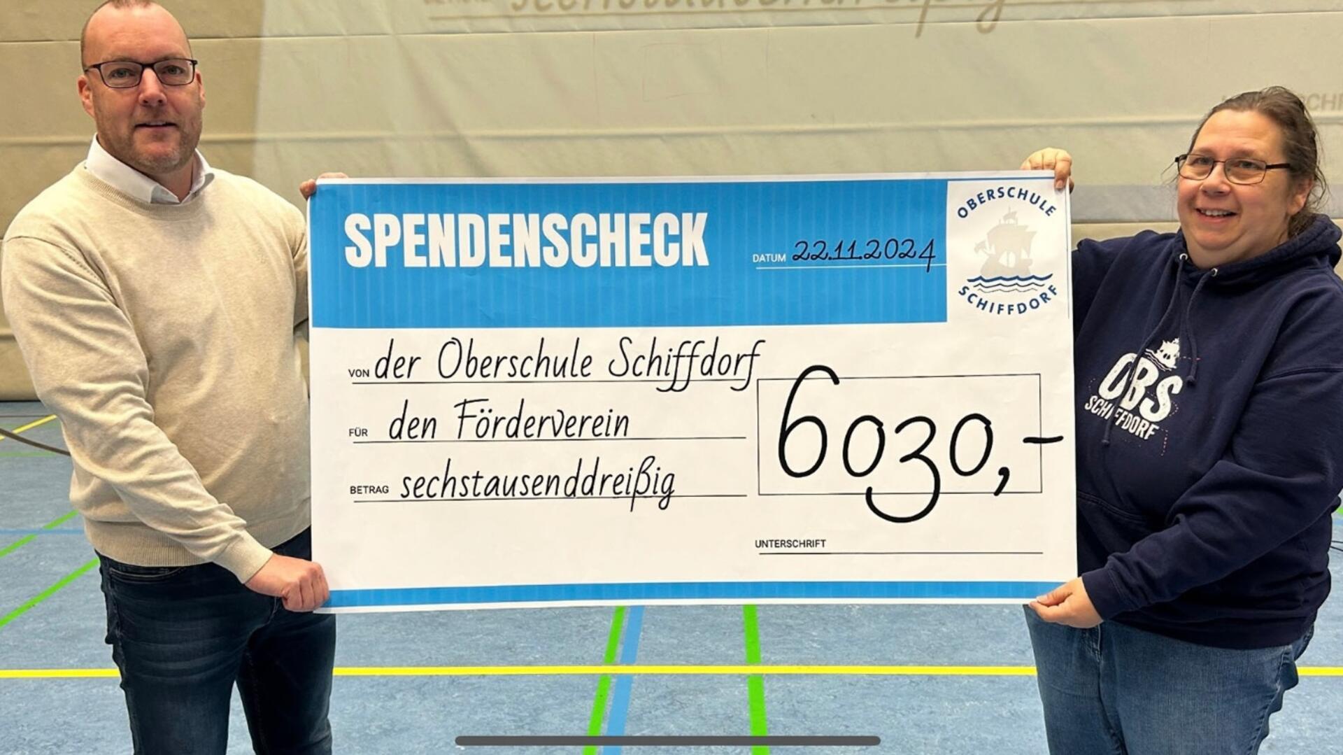 Ein Mann und eine Frau halten einen symbolischen Scheck von 6.030 Euro in die Höhe. 