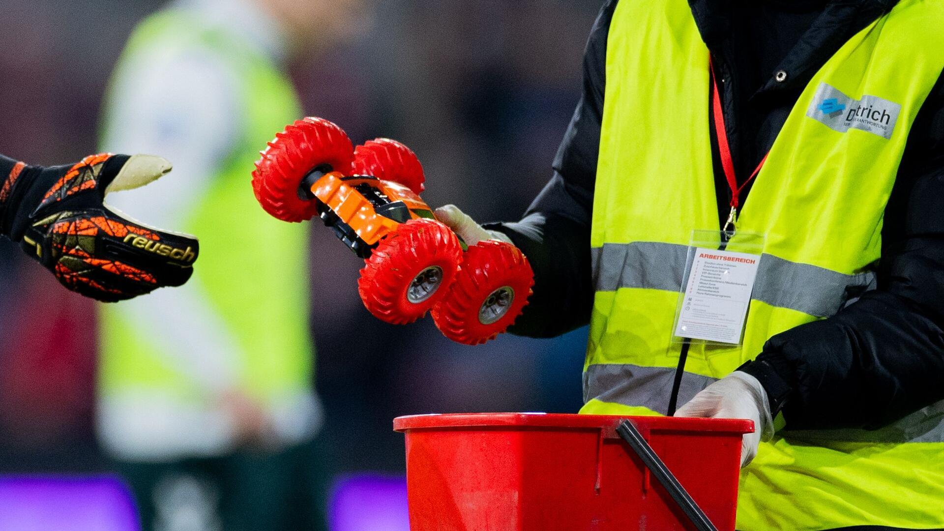 Bremens Torwart Michael Zetterer gibt einem Ordner ein ferngelenkte Auto. Es war in der Partie im RheinEnergieStadion auf dem Spielfeld gefahren.