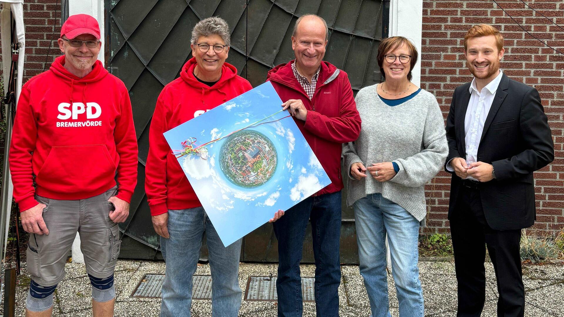 Bremervördes Ortsbürgermeister Dirk-Frederik Stelling (rechts) überreichte Pastor Volker Rosenfeld (Mitte) ein ganz besonderes Geschenk: eine Luftaufnahme der Stadt Bremervörde im Stil eines Kugelbildes der Kernstadt