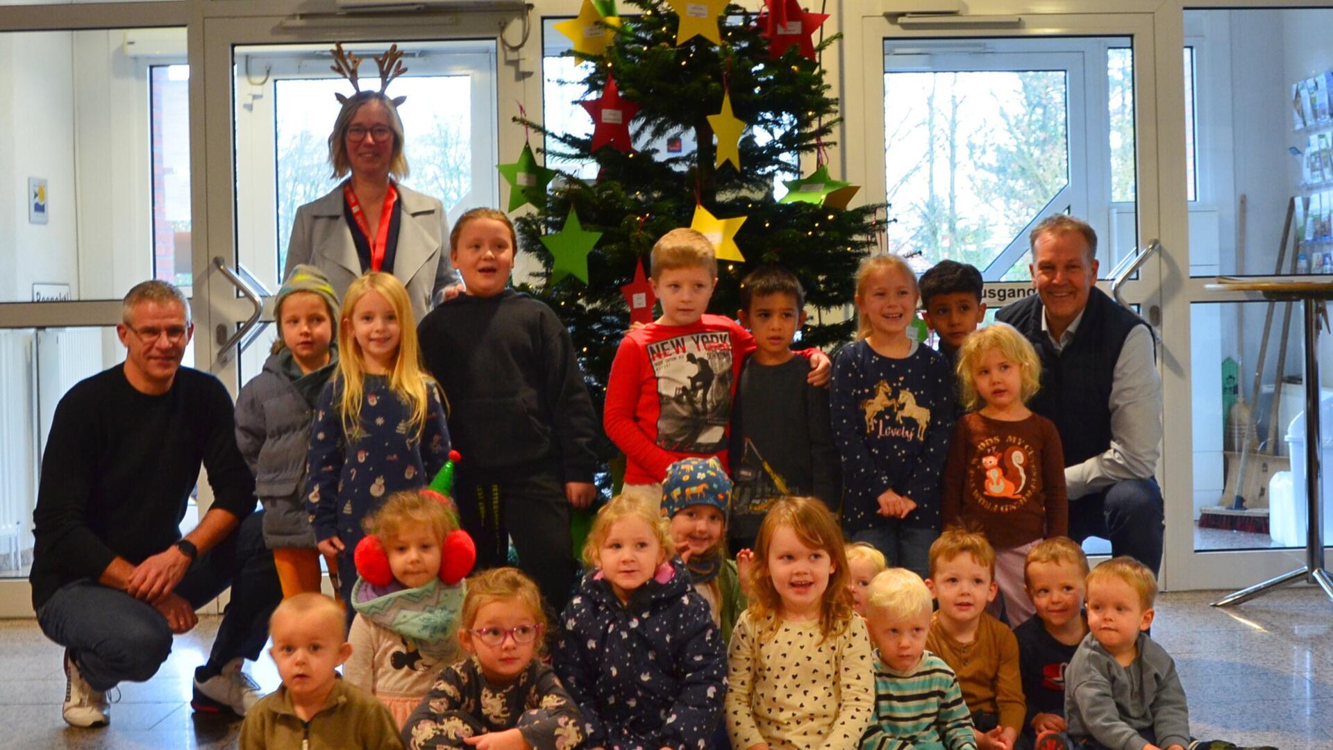 Bürgermeister Guido Dieckmann (hinten rechts) mit der Ersten Gemeinderätin Claudia Lühmann (hinten links stehend), dem Projektverantwortlichen Kai Wilkens (hinten links) und den Kita-Kindern vor dem geschmückten Wunschbaum im Beverstedter Rathaus.