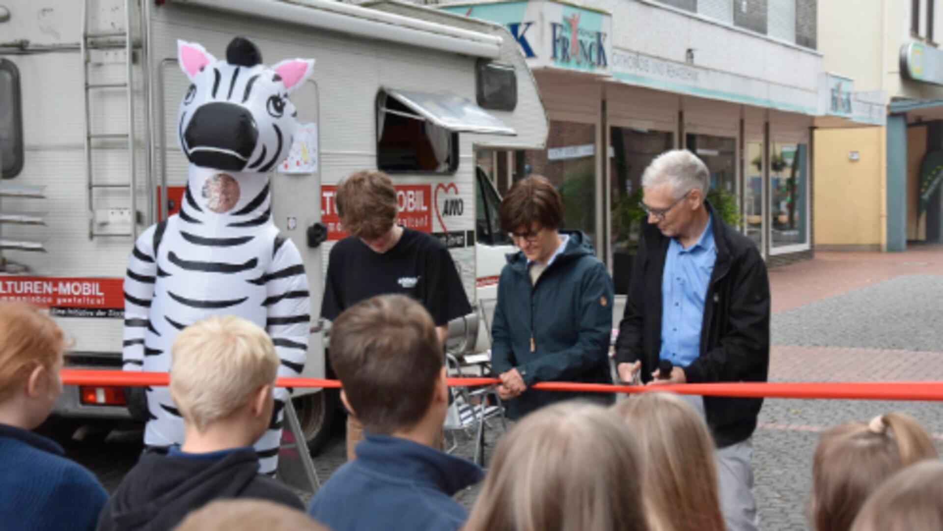 Das Foto zeigt, wie drei Personen ein rotes Band durchschneiden. 