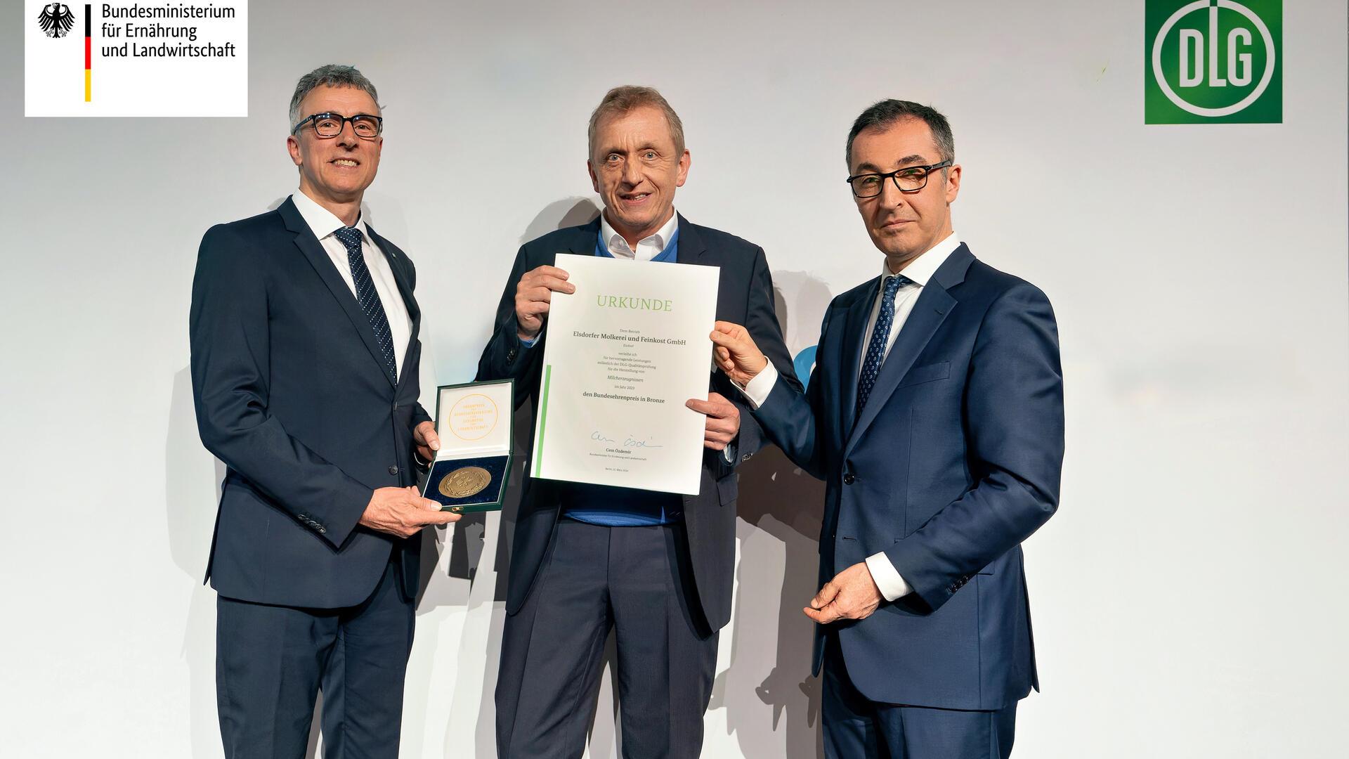 Bundesminister Cem Özdemir überreicht Urkunde und Medaille gemeinsam mit DLG-Vizepräsident René Döbelt auf dem 14. Berliner Milchforum an Olaf Hausschild.