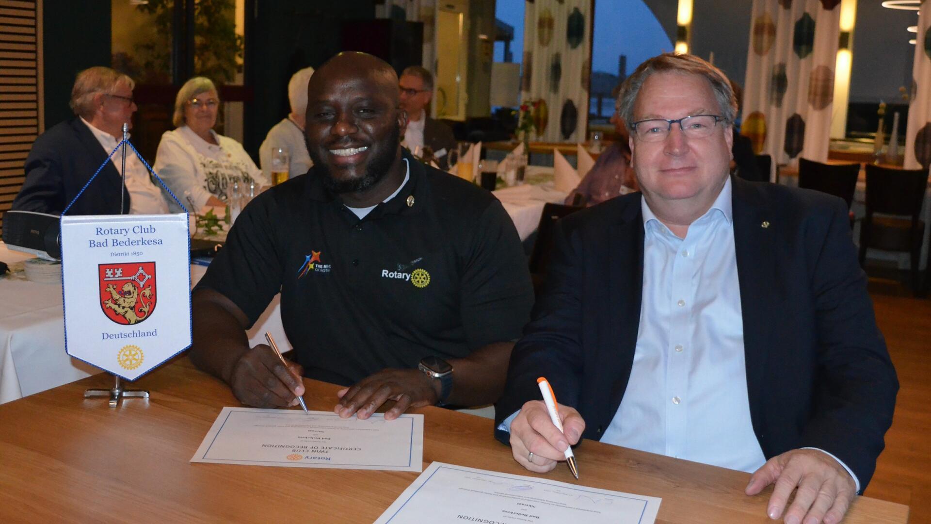 Chama Chishimba (links) und Claas Festerling besiegeln die Freundschaft zwischen dem Rotary Club Nkwazi und dem Beerster Rotary-Club mit ihrer Unterschrift auf der Partnerschaftsurkunde.