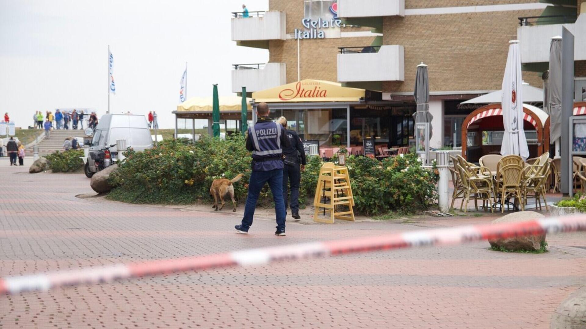 Das Bild zeigt das von der Polizei abgesperrte Umfeld des Tatorts: Mit einem Suchhund fahnden Beamte am Vormittag nach der Auseinandersetzung nach der Tatwaffe.