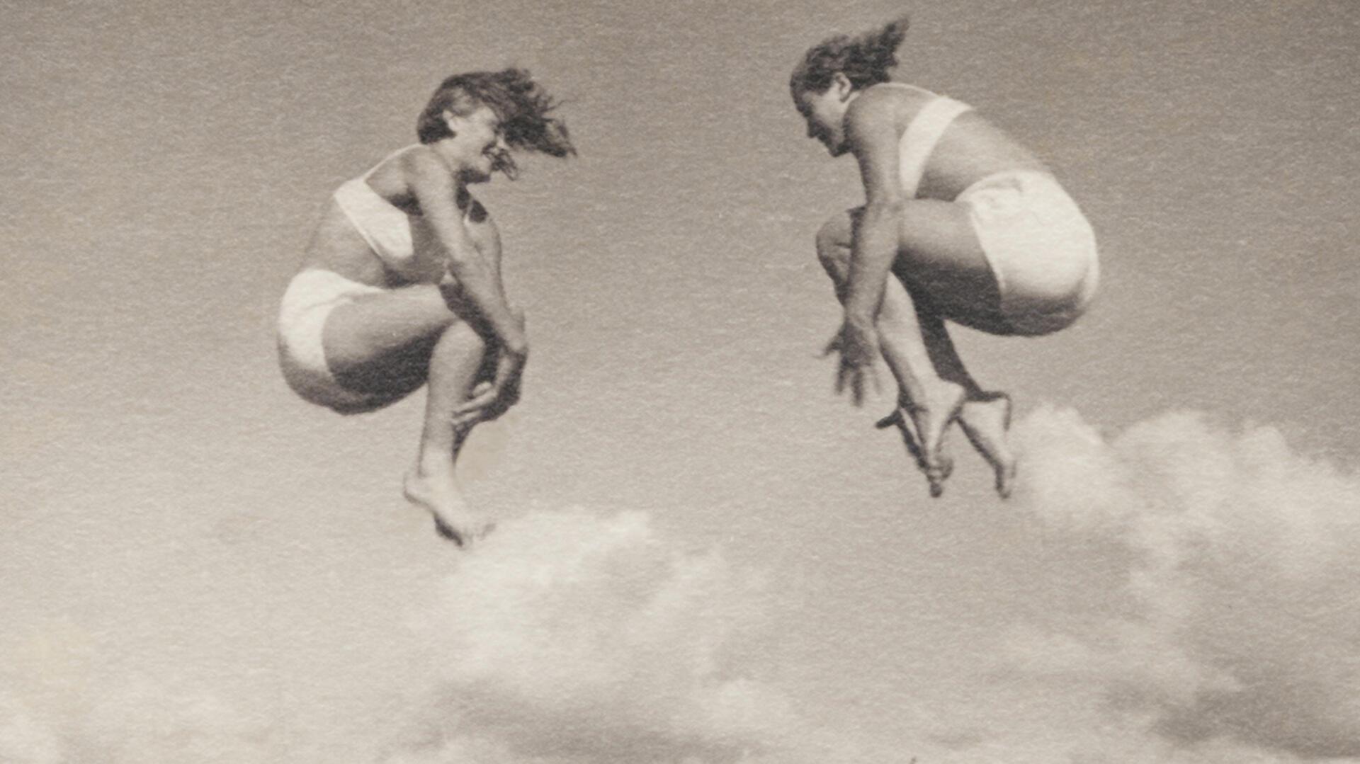 Historisches Foto zweier Frauen mitten im Sprung mit angezogenen Beinen