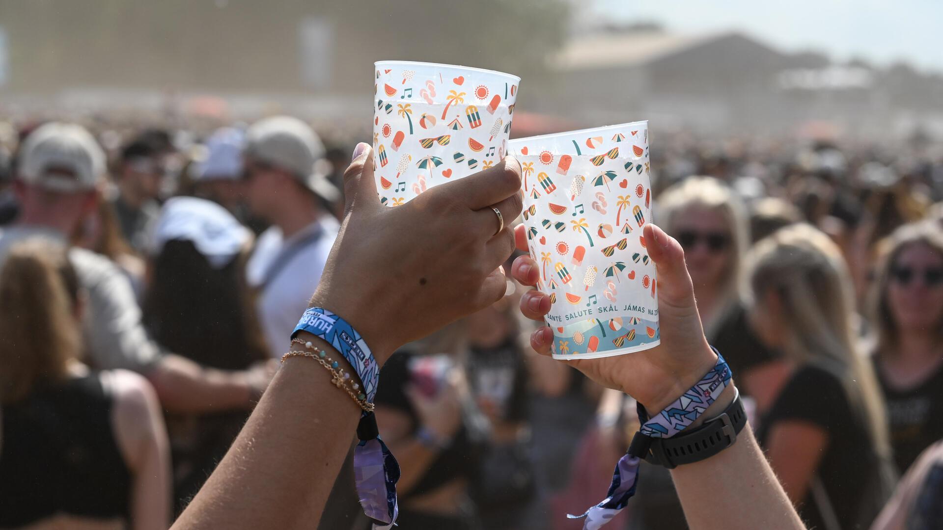 Menschen halten zwei Becher hoch und stoßen an. 