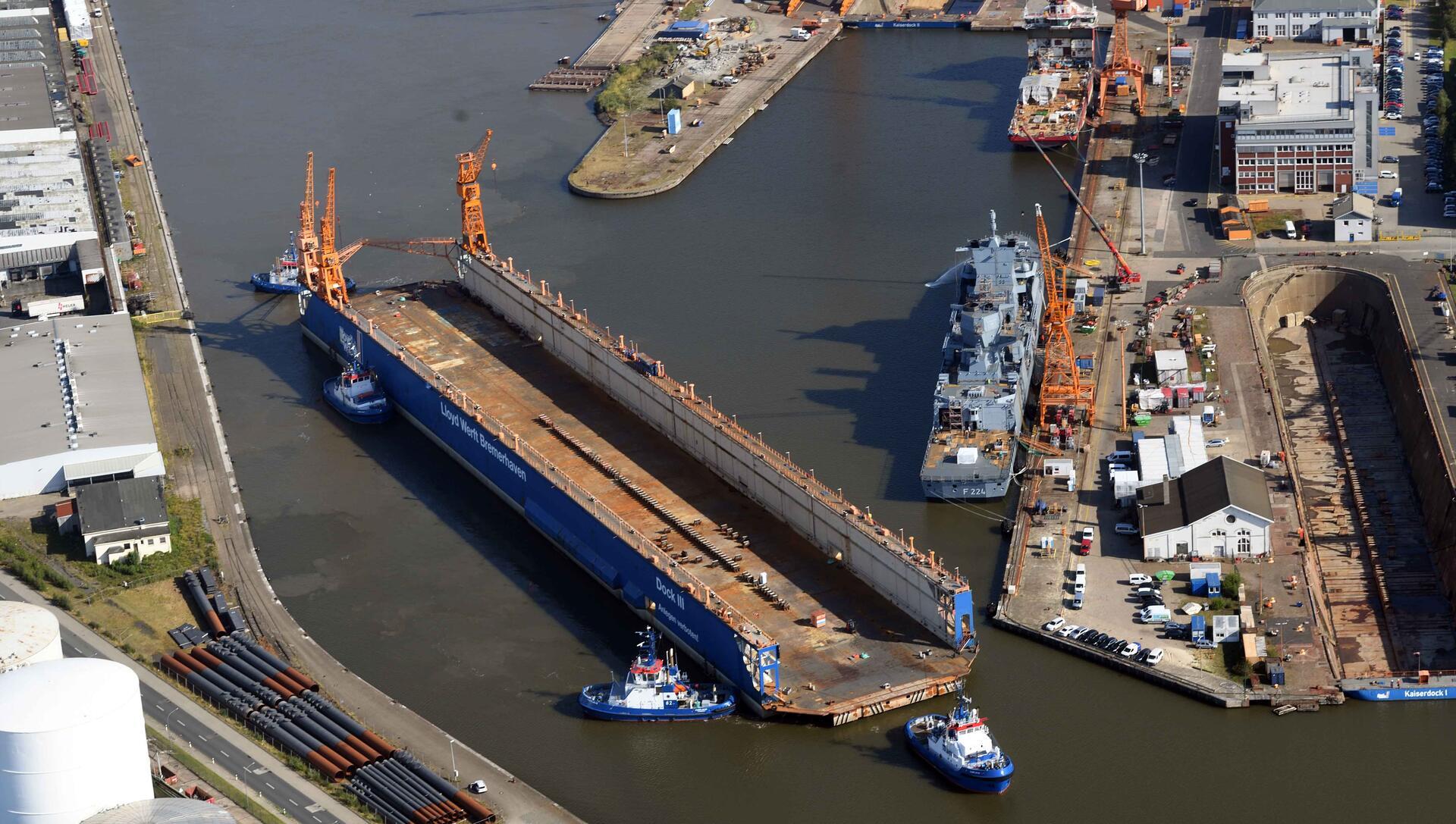 Das Schwimmdock der Lloyd Werft wird von vier Schleppern zum Kaiserhafen gebracht.