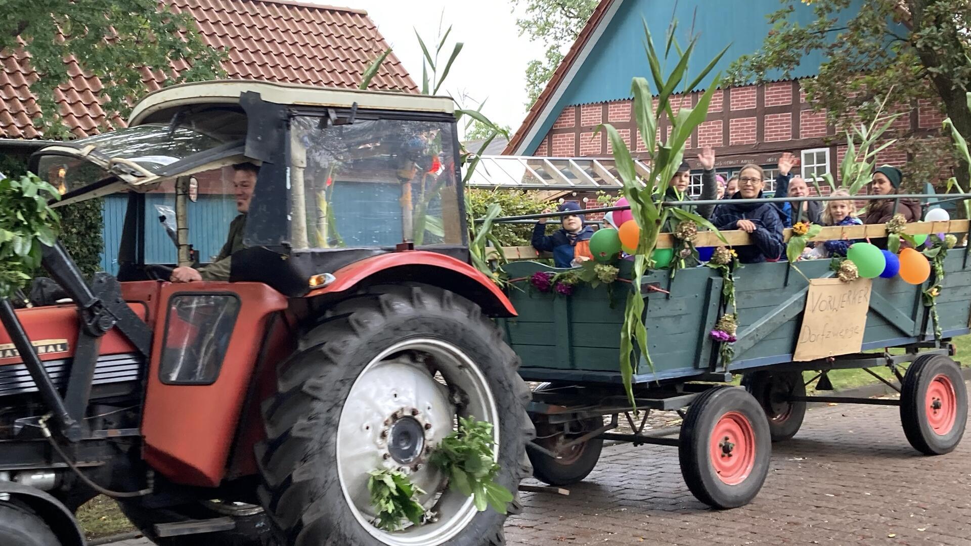 Zwei Trecker fahren bei einem Festumzug durch ein Dorf.