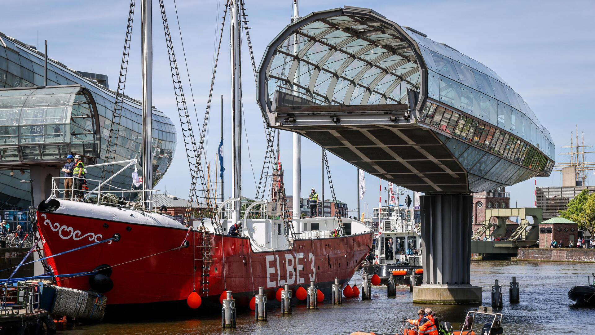 Das sanierte Feuerschiff „Elbe 3" passiert auf seinem Weg von der Bredo-Werft bis zum Liegeplatz im Museumshafen des Deutschen Schifffahrtsmuseums in Bremerhaven auch die Havenwelten, muss durchs Nadelöhr zweier Klappbrücken und der aufgeschwenkten Glasbrücke vorbei am Klimahaus.