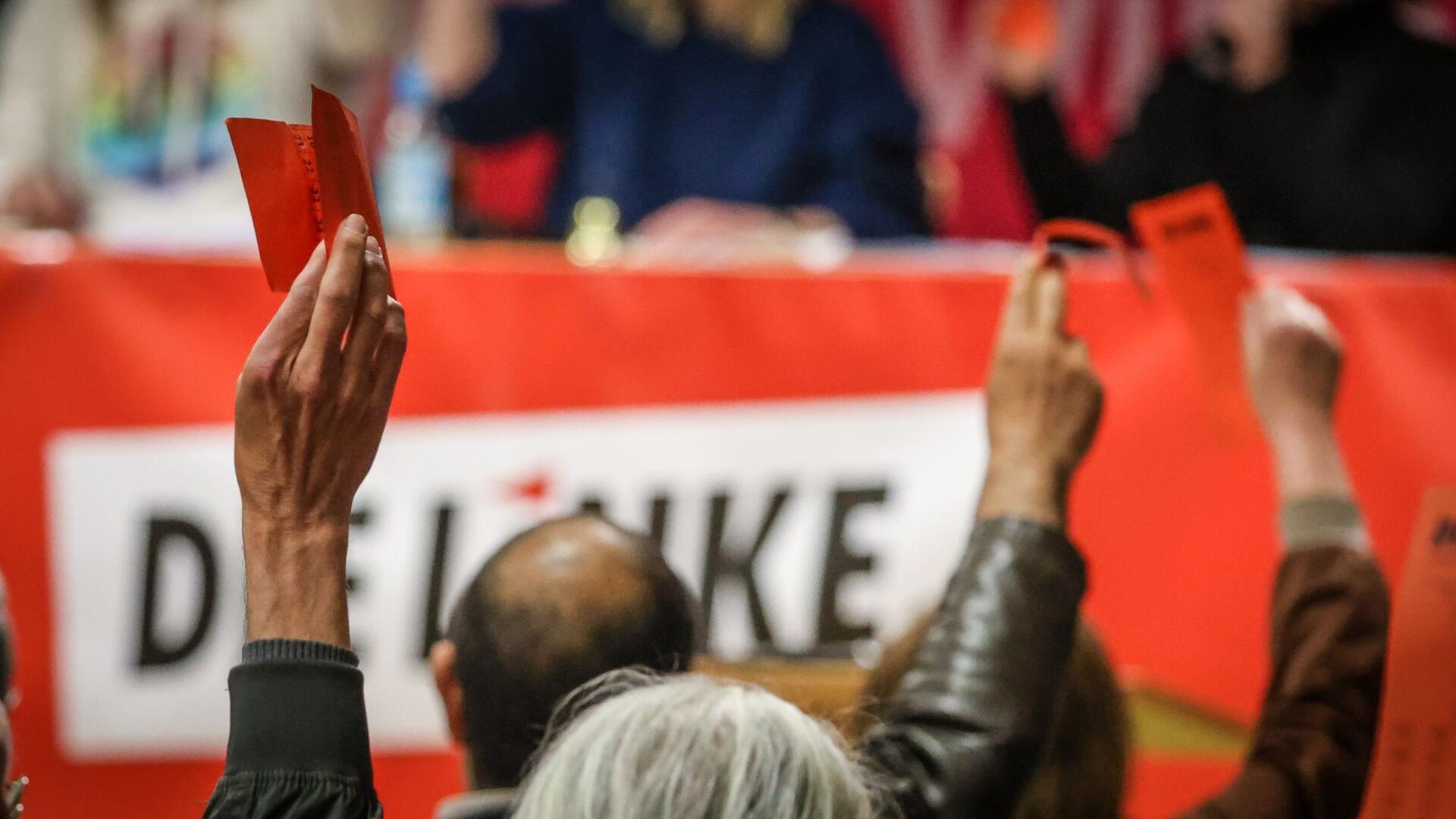 Delegierte heben bei einer Abstimmung auf einem Landesparteitag der Partei Die Linke ihre Stimmkarten.