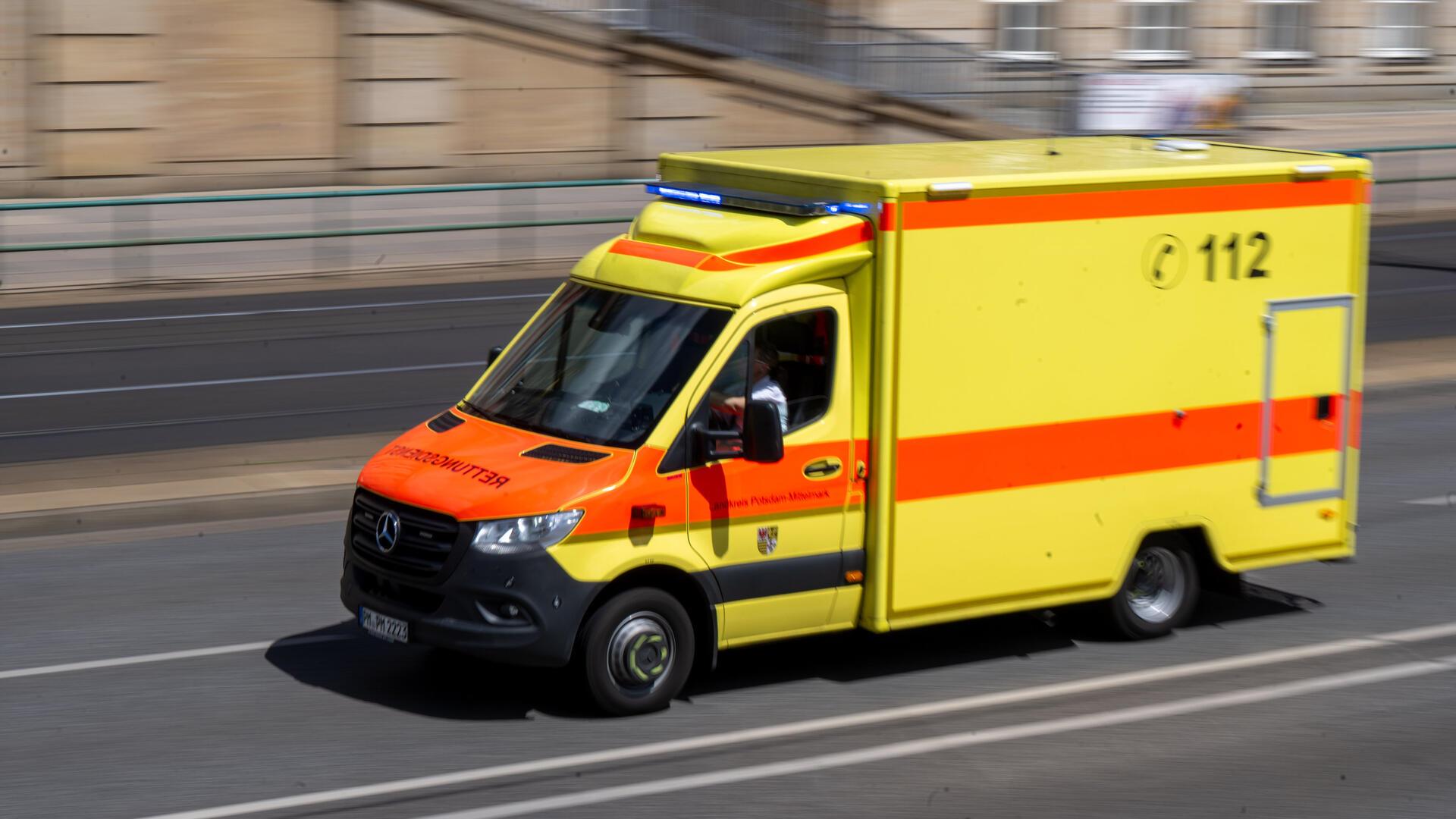 Ein Rettungswagen mit Blaulicht fährt über eine Straße.