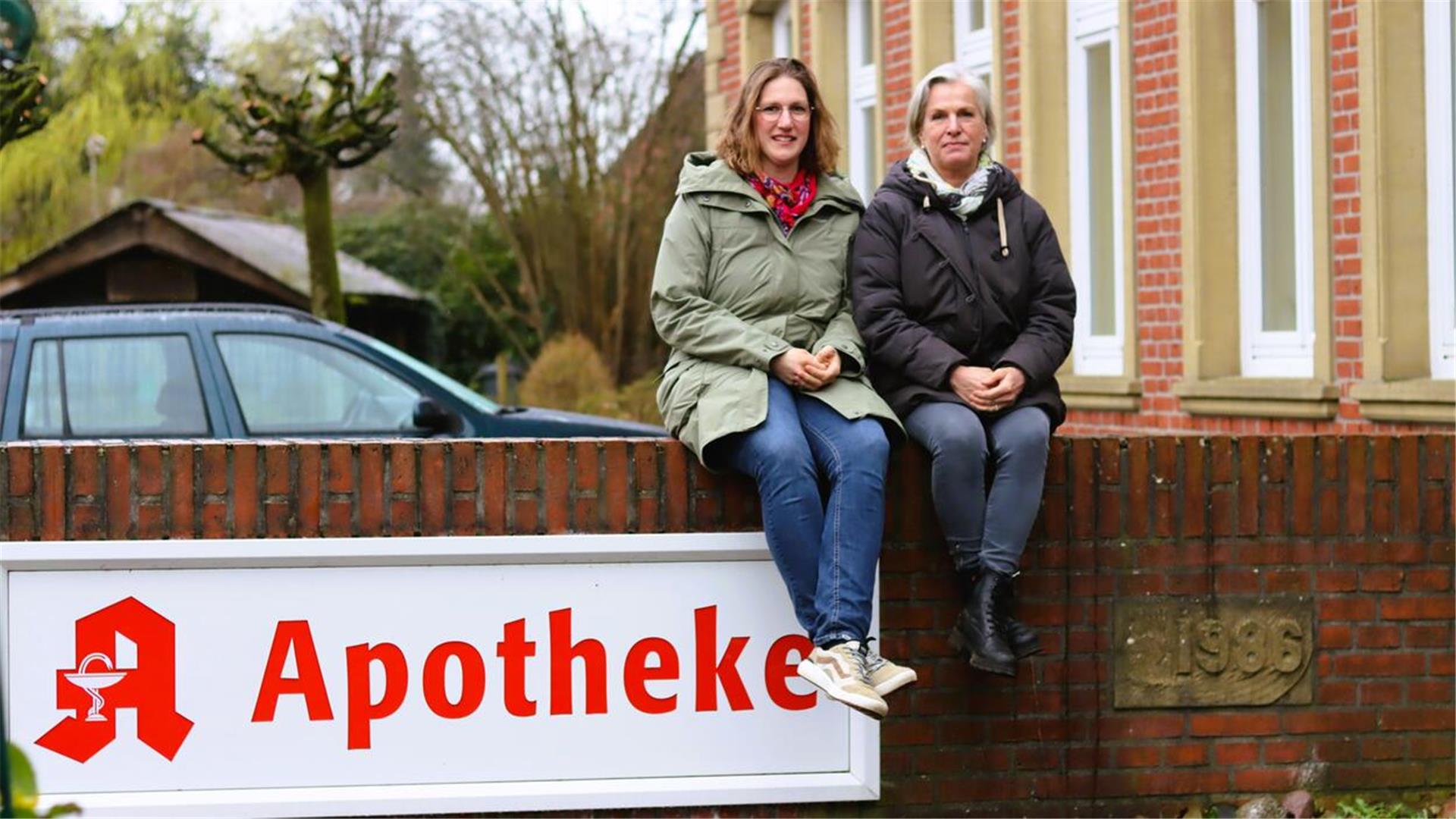 Zwei Frauen sitzen auf einer Mauer.