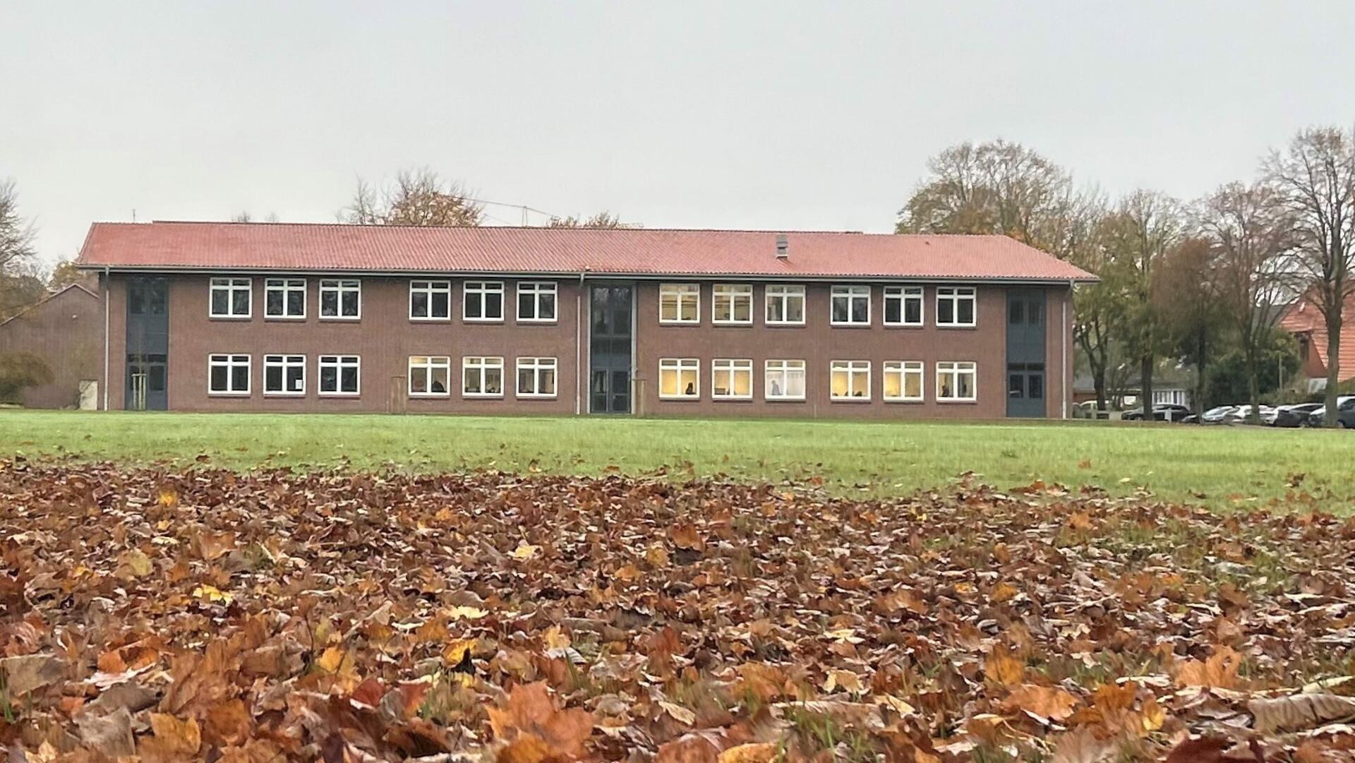 Auf einer Wiese steht ein Schulgebäude aus rotem Backstein.