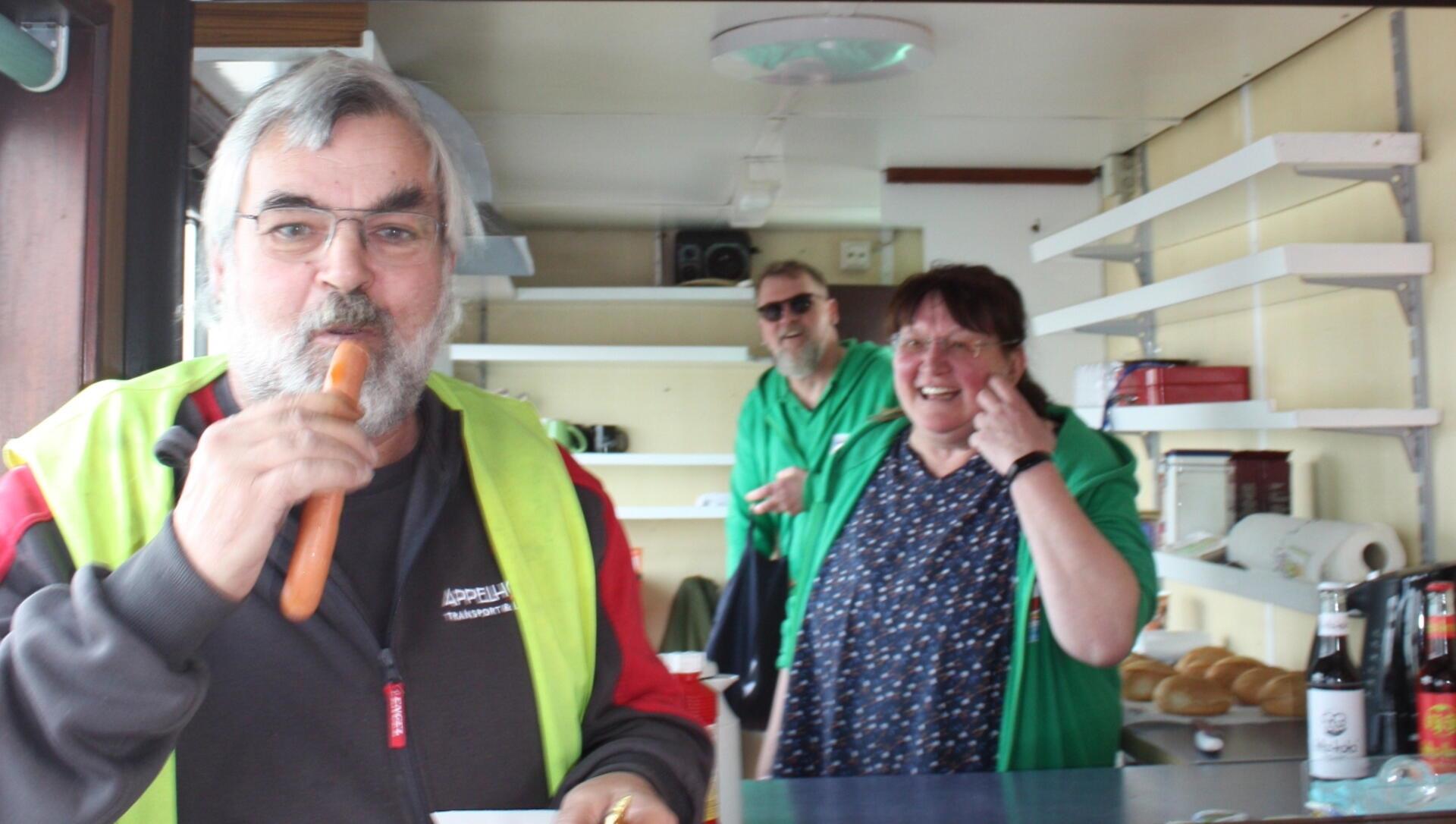 Der Milchwagen-Fahrer Christian Horbach (links) freute sich, endlich wieder mal eine Bockwurst auf der Fähre zu genießen, die Doris Walleit (rechts) und Axel Popanski (mitte) von Hagener Fairtrade-Steuerungsgruppe anboten. 